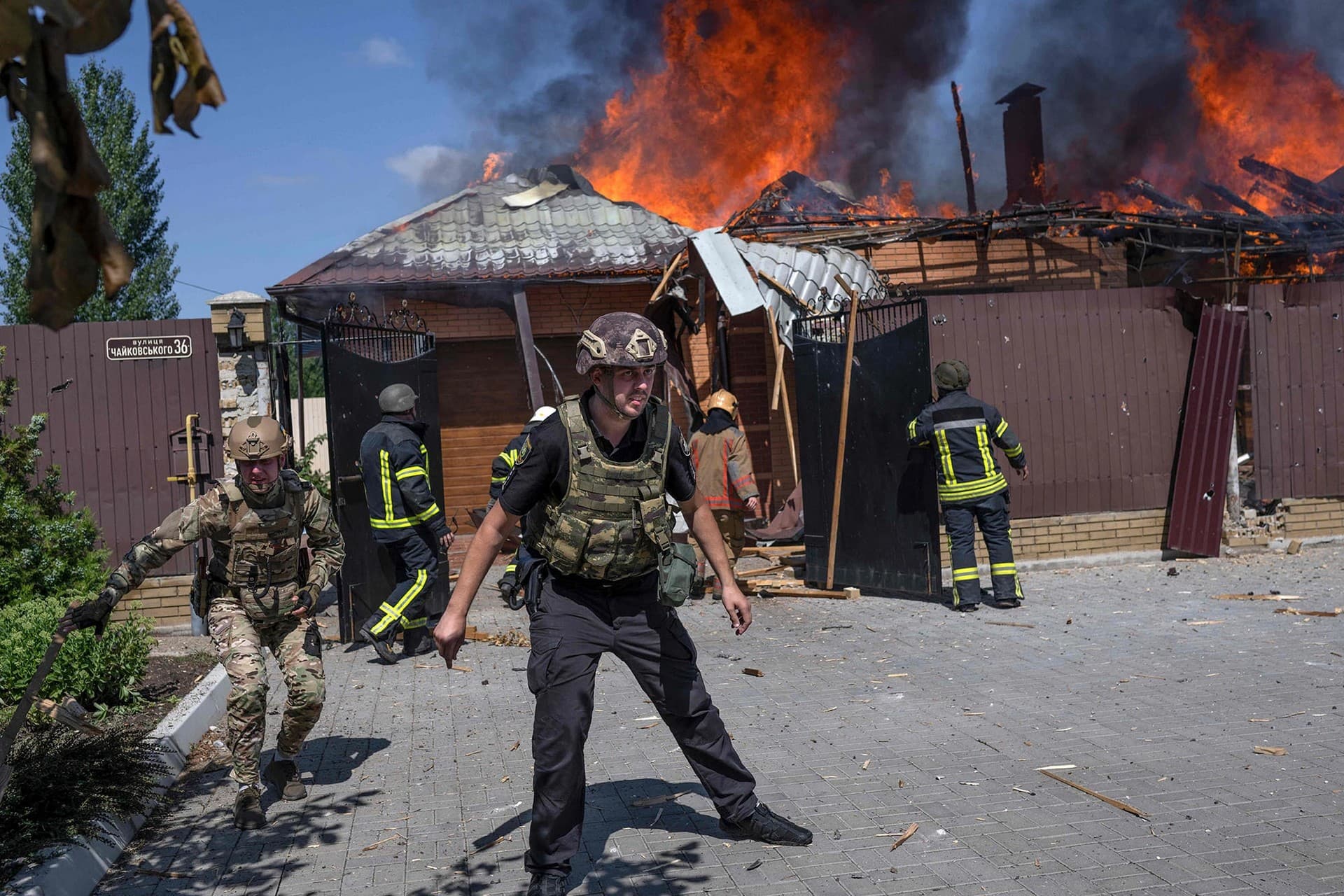 Ukrainian soldiers stand in front of a burning house on the outskirts of Bakhmut