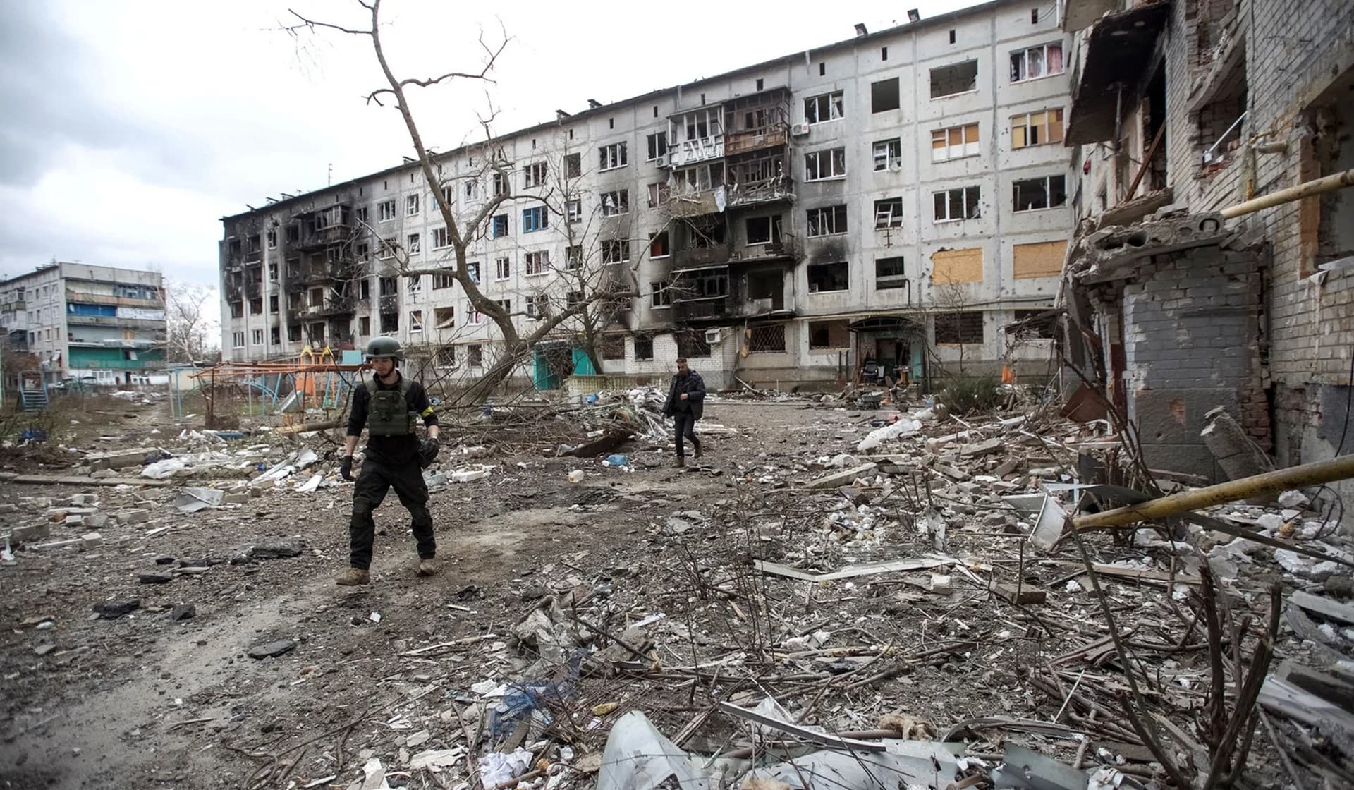 British volunteers Chris and Dave search for local residents to evacuate in a yard of a damaged apartment building in Bakhmut