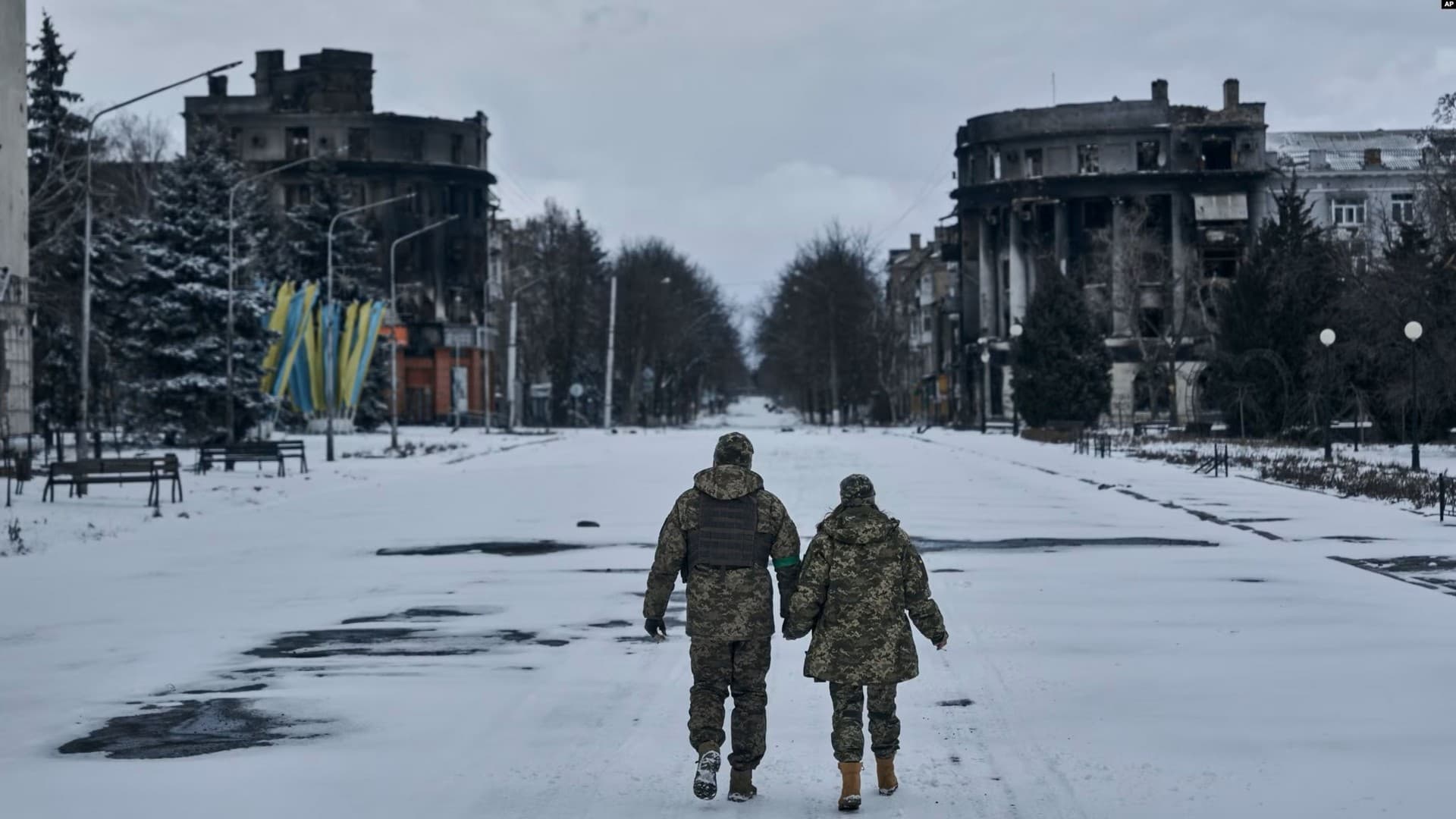 Ukrainian soldiers walk along a street lined with damaged buildings in Bakhmut