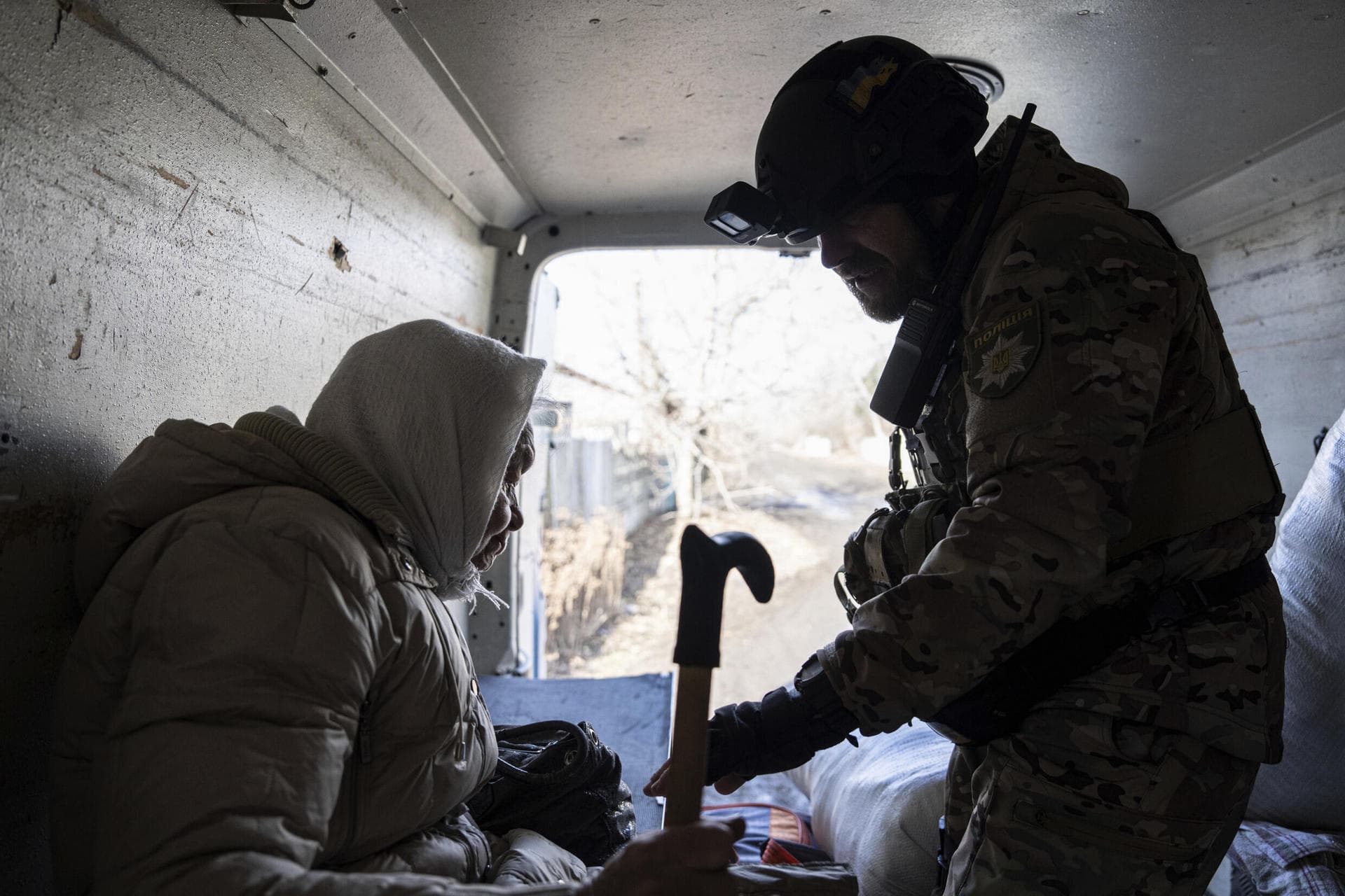 A Ukrainian police officer helps en elderly woman as she evacuates to safe areas in Chasiv Yar
