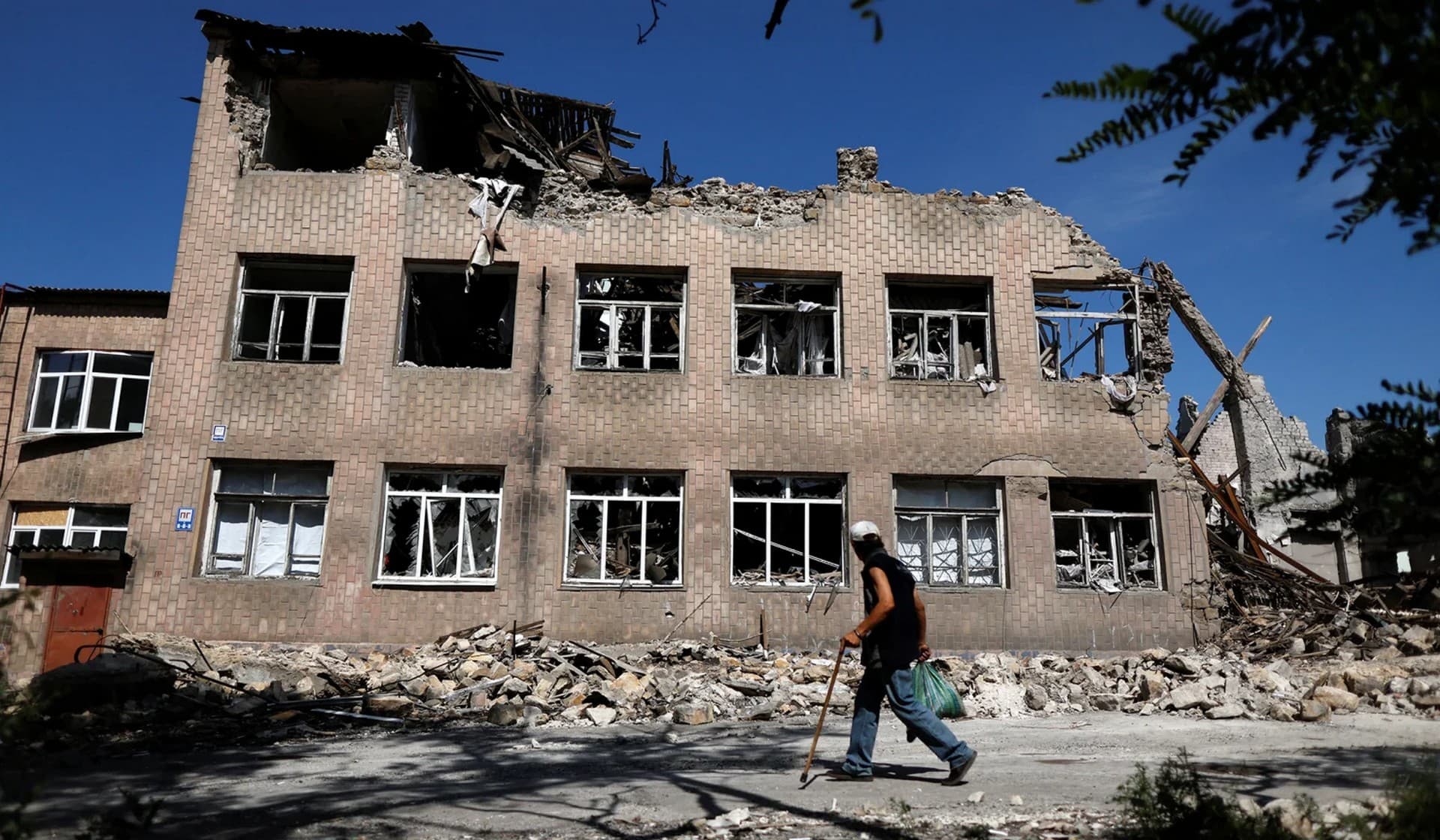 A man walks near a destroyed school in Toretsk