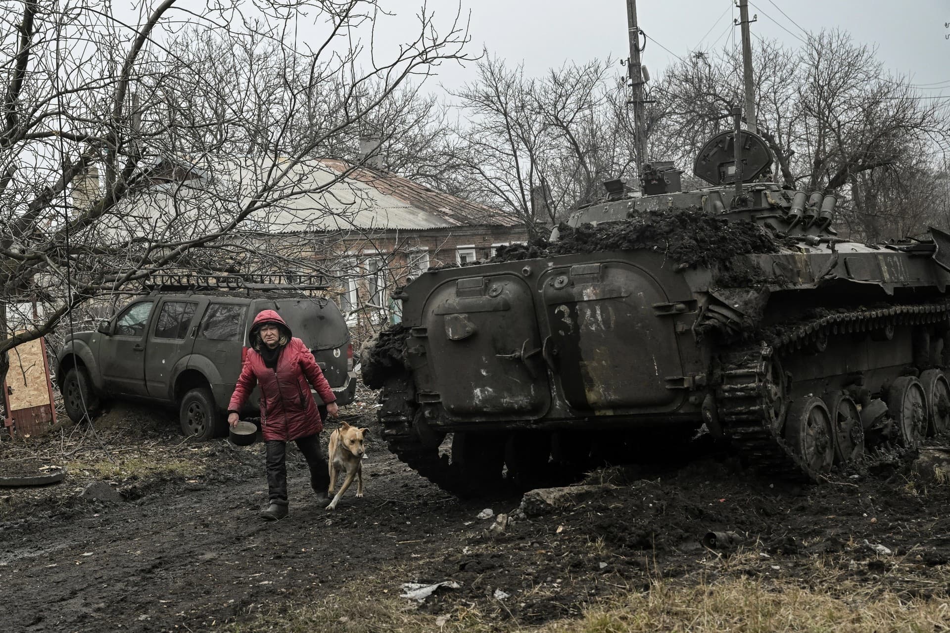 A woman walks past a destroyed BMP-2 tank after shelling in the village of Chasiv Yar