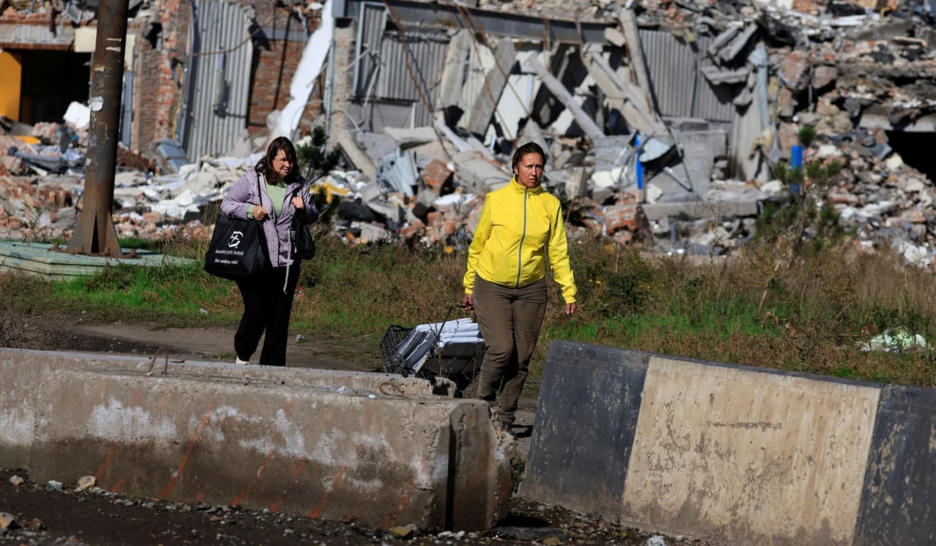 Local residents walk past a destroyed building in Bakhmut