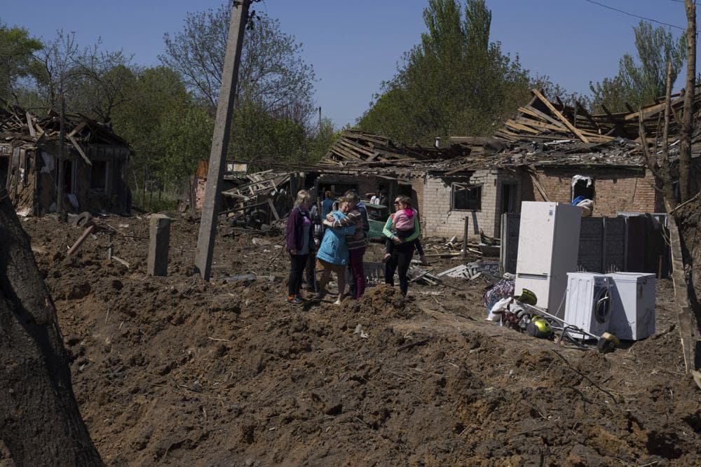 People react as they stand next to a crater in destroyed residential area after Russian airstrike in Bakhmut