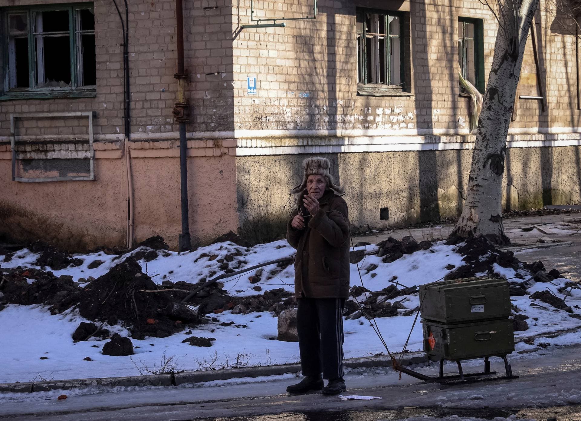 A resident rests as he walks with empty ammunition boxes on a street, as Russia's attack on Ukraine continues, in the front-line city of Bakhmut