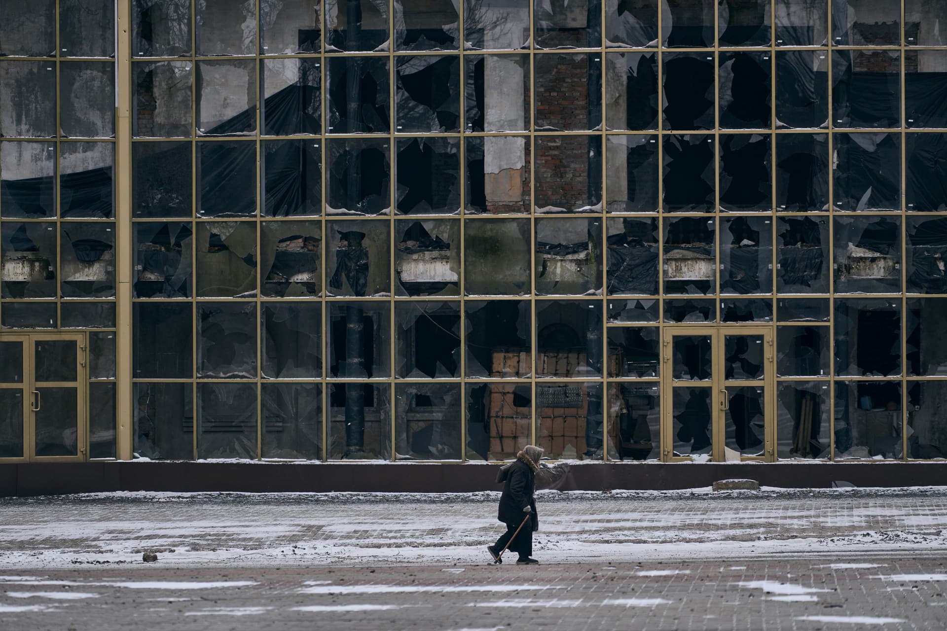 A local resident walks along a street past damaged buildings in Bakhmut
