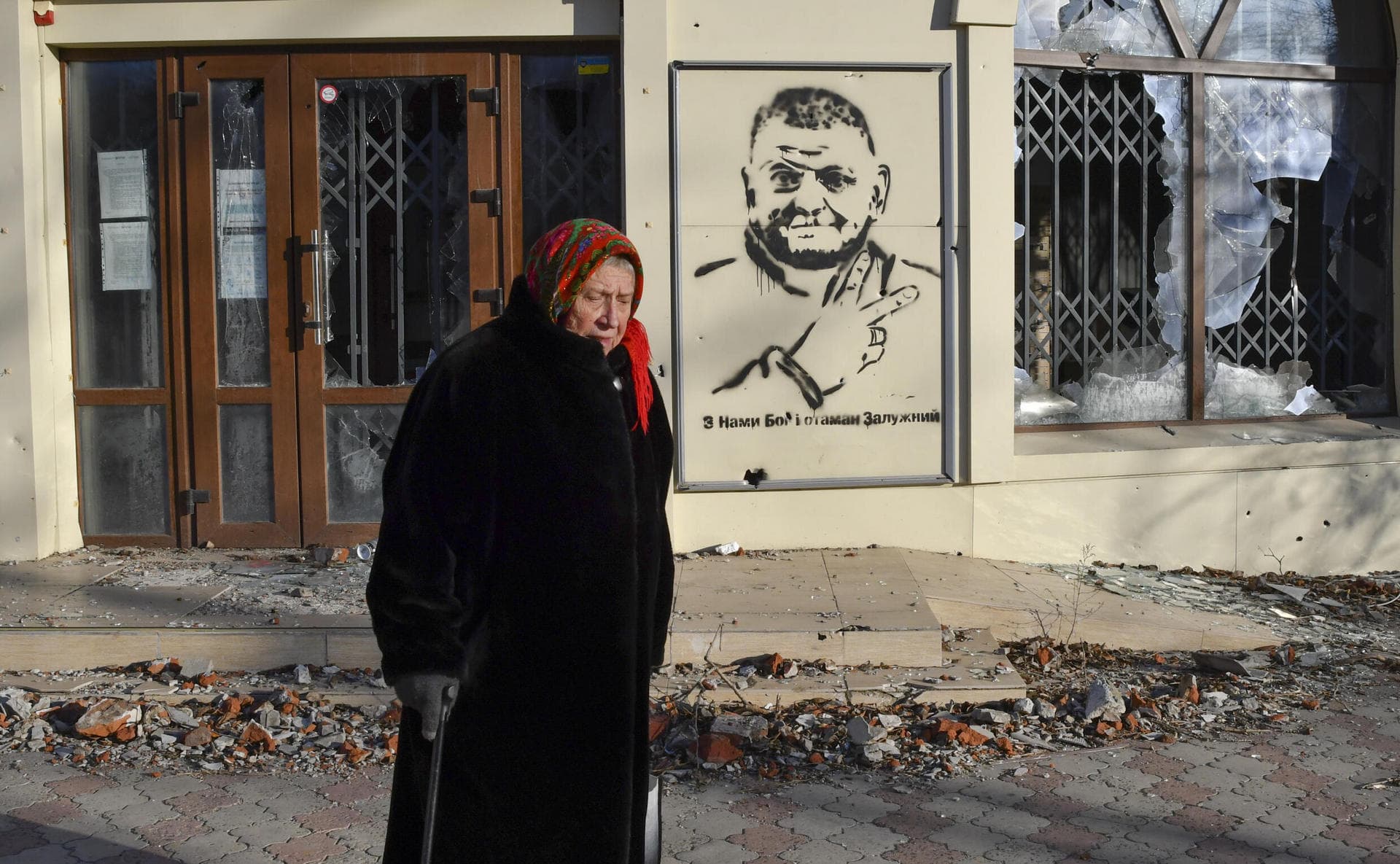 An elderly woman walks along a street against background of a graffiti depicting General Valery Zaluzhny in Bakhmut