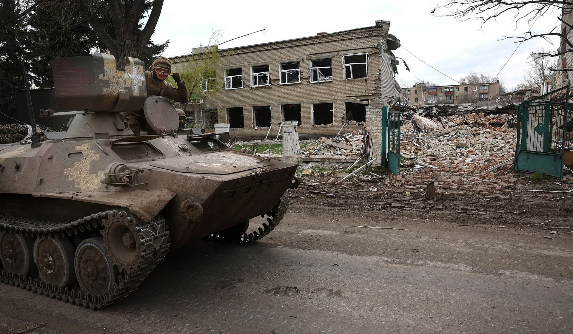 Ukrainian servicemen ride pass the destroyed school building on the way to the frontline near Chasiv Yar