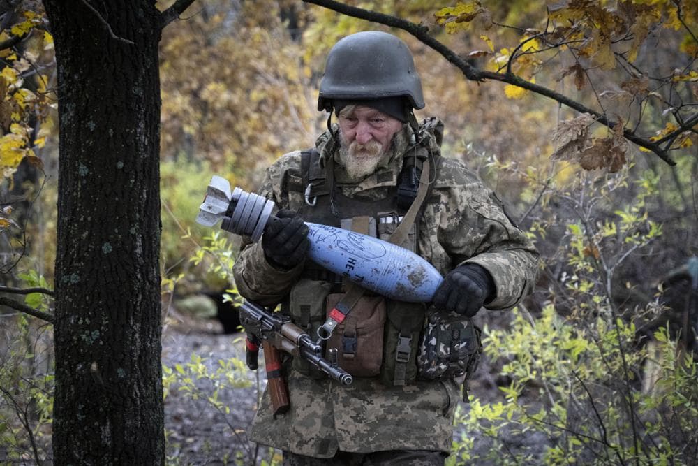 A Ukrainian soldier carries a shell with a written message to the Russian army near Bakhmut