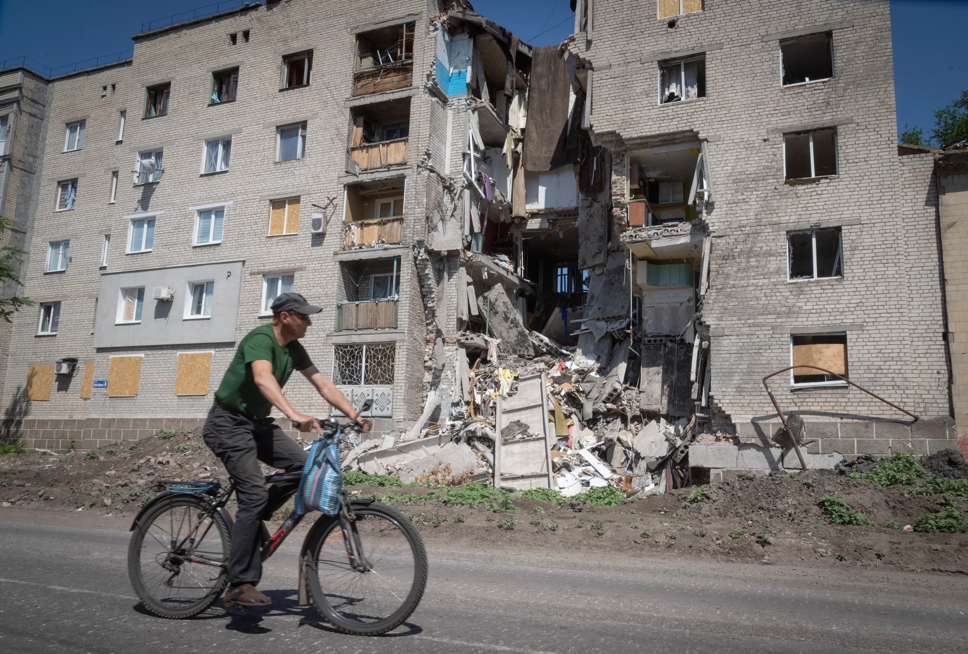 A man rides a bicycle past a building damaged in Russian shelling in Bakhmut