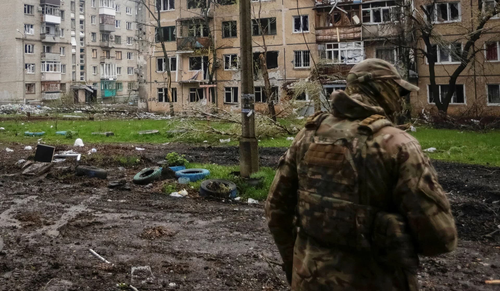 A Ukrainian service member walks near residential buildings damaged by a Russian military strike in the front line town of Bakhmut