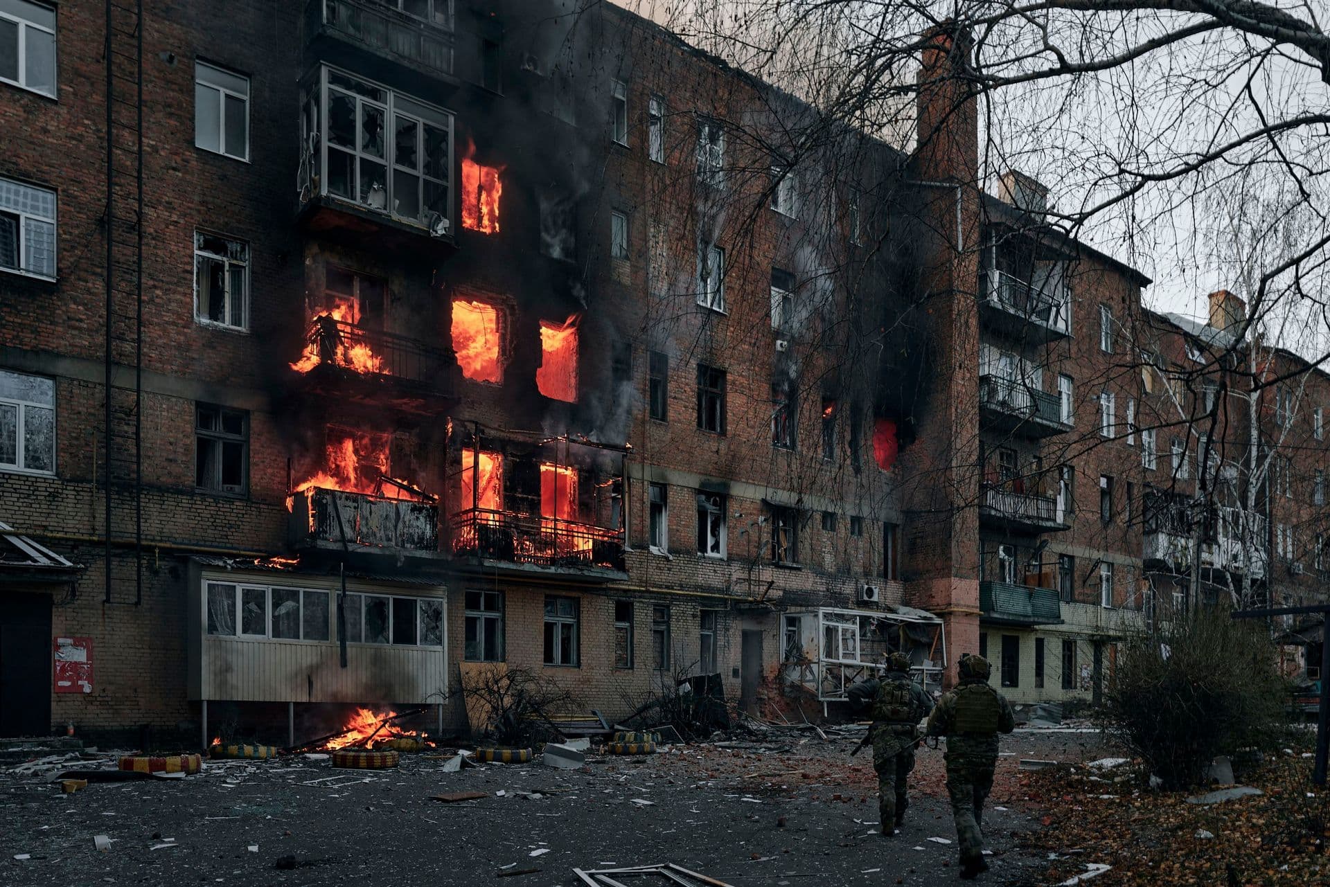Ukrainian soldiers run to help people in an apartment building on fire after Russian shelling in Bakhmut