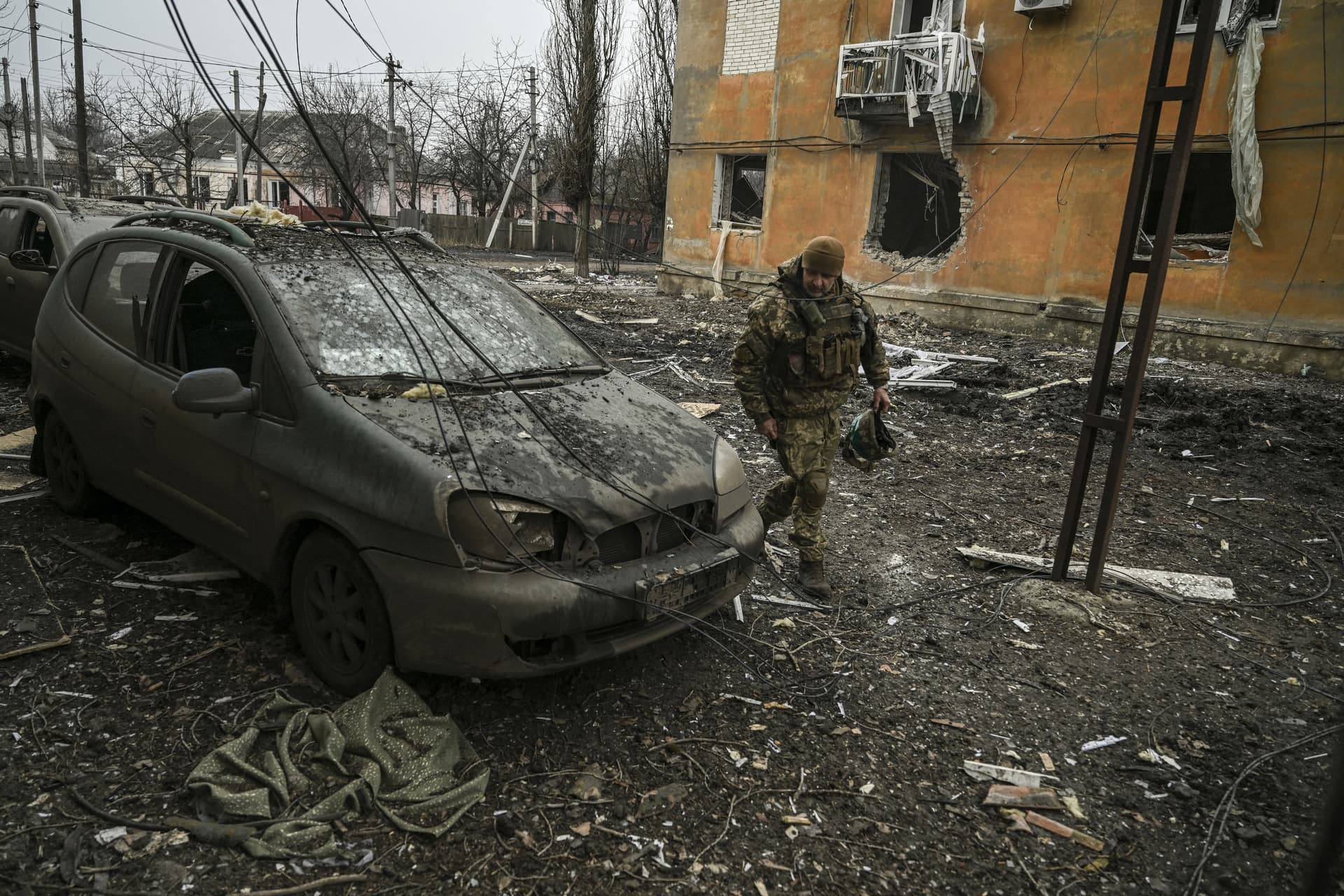 A Ukrainian service member looks at a damaged car after a shelling in the village of Chasiv Yar
