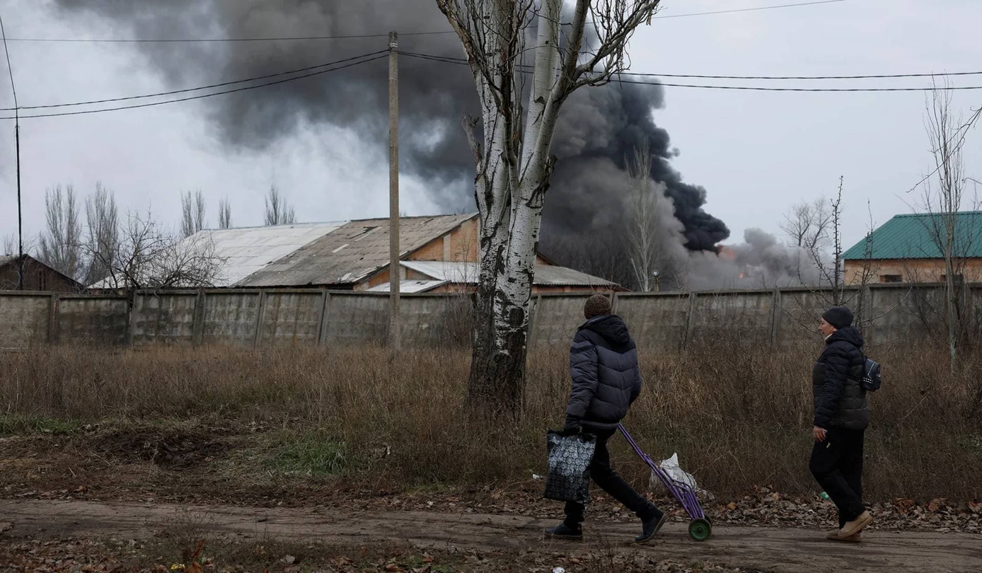 Volodymyr and Nataliia  walk past an industrial building that hit in a missile strike during intense shelling on Christmas Day at the frontline in Bakhmut