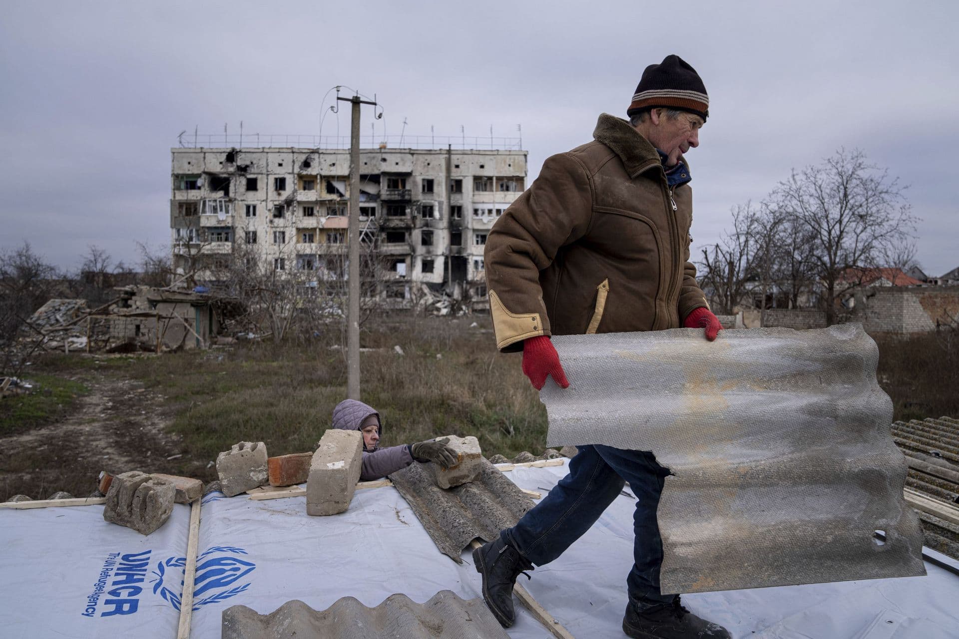 Mykola helps his neighbour to repair a roof in the recently retaken town of Arhanhelske