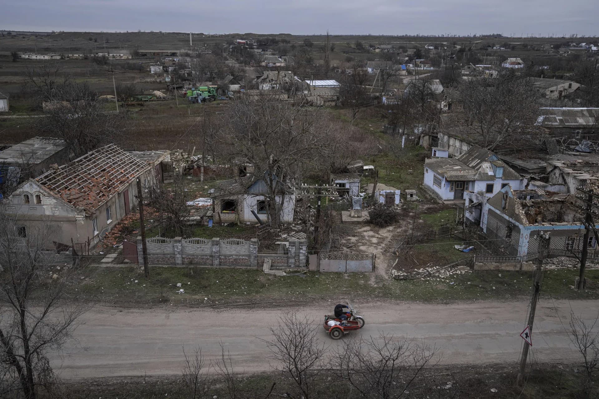 A man rides a motorbike in front of houses which have been destroyed during the fighting between Russian and Ukrainian forces in the recently liberated town of Arhanhelske