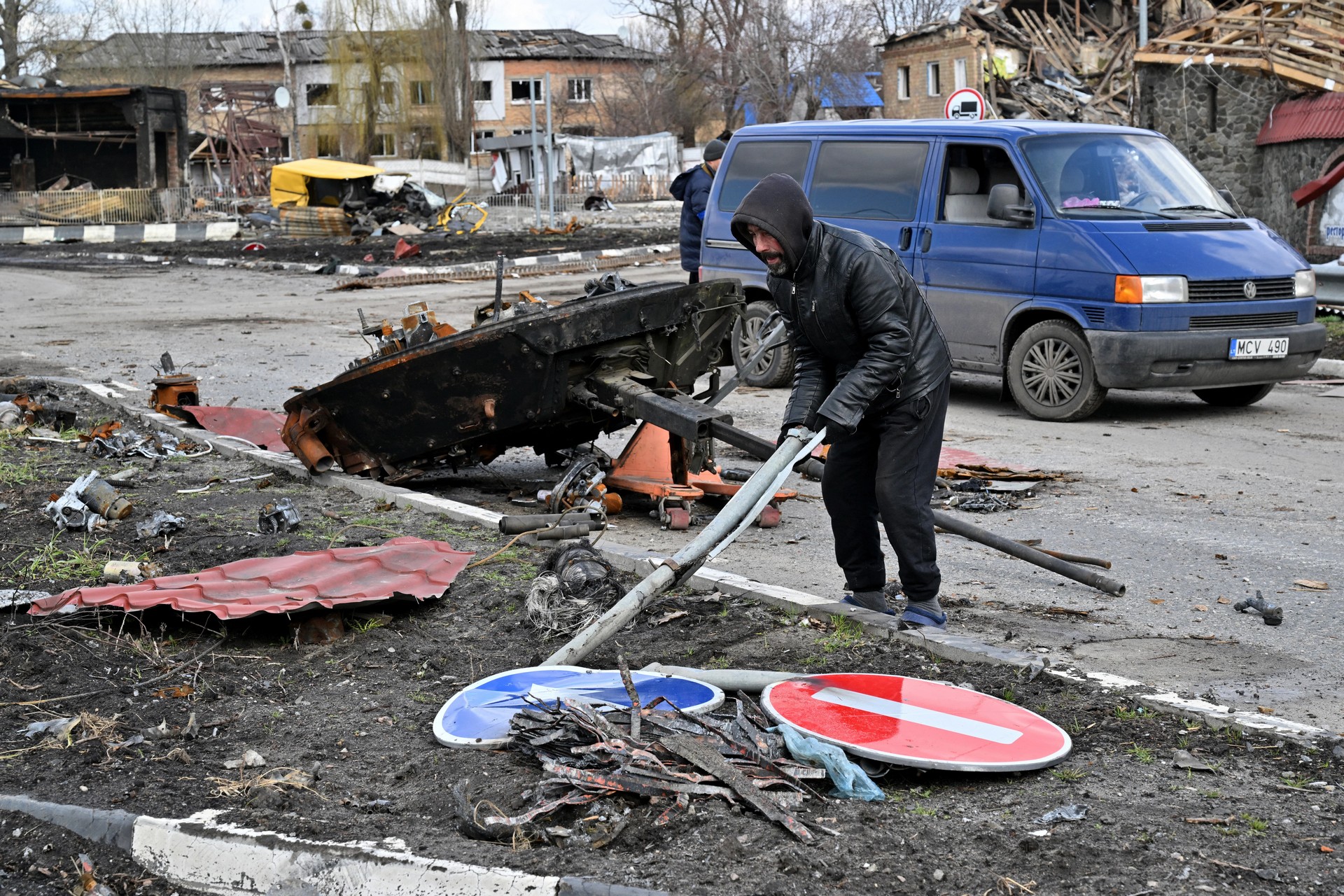 man removes debris near destroyed Russian armoured personnel carrier in Borodianka