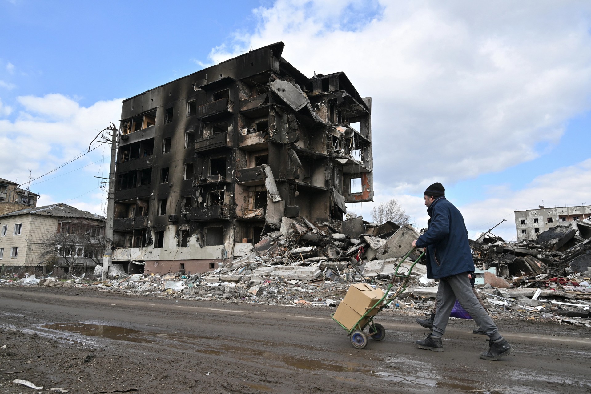 man walks past destroyed buildings