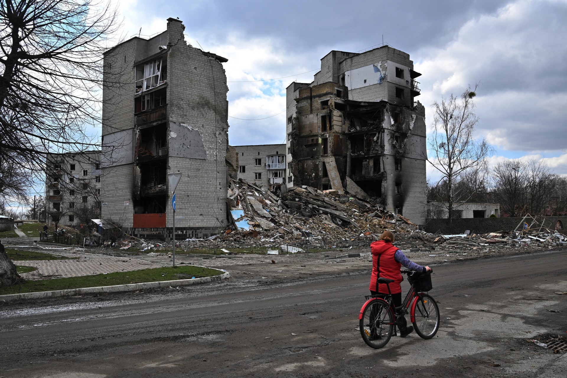 woman walks past destroyed buildings in Borodianka