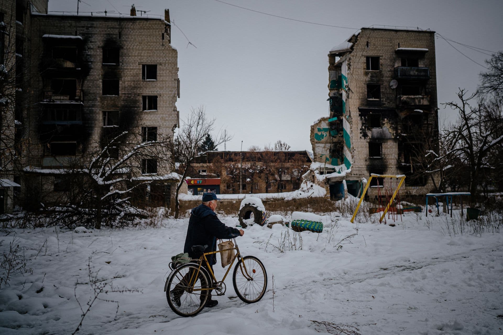 A man pushes his bike next to destroyed residential buildings in Borodyanka