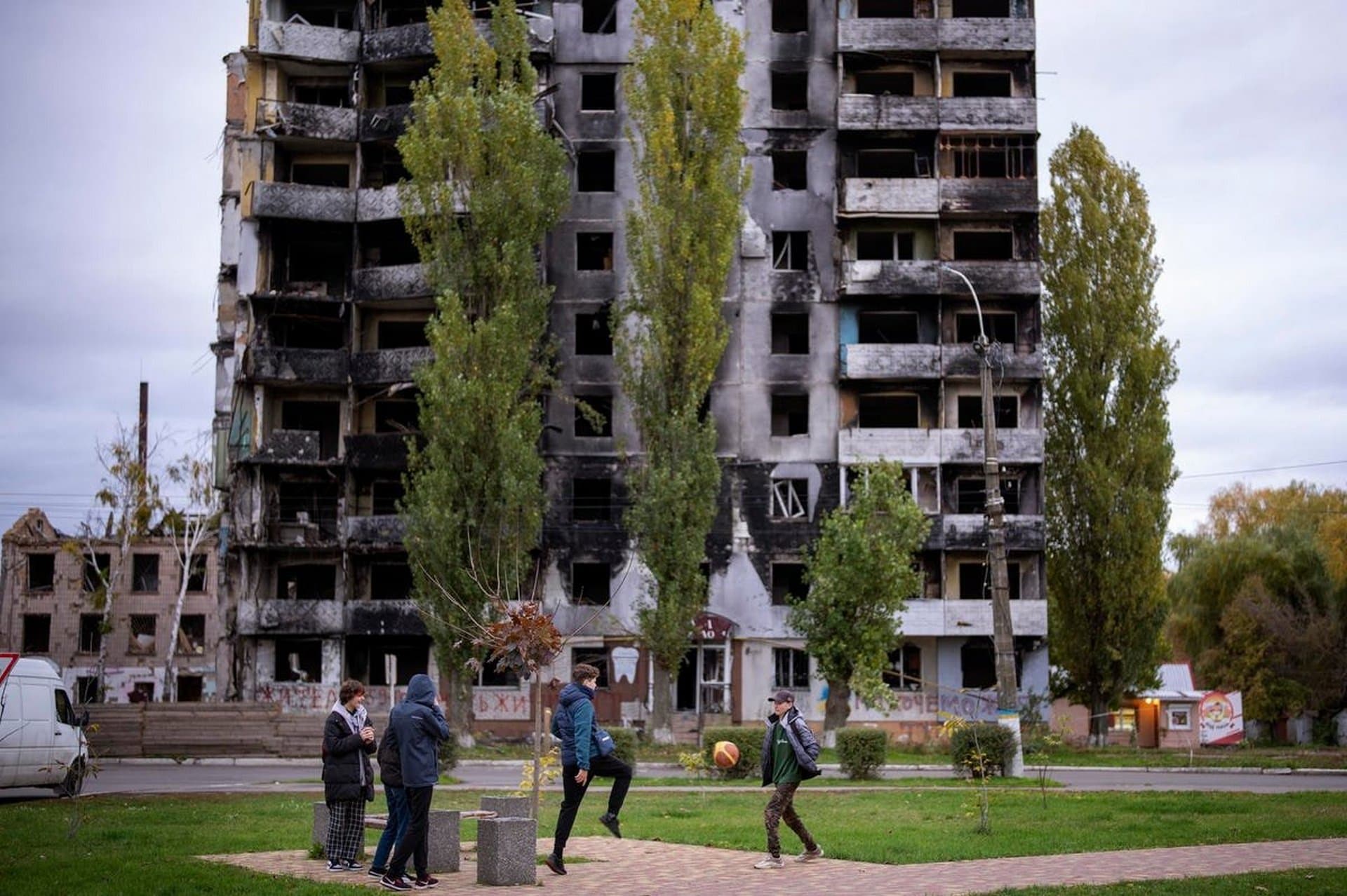 Children play soccer near a building damaged by fighting between Ukrainian and Russian forces in Borodyanka
