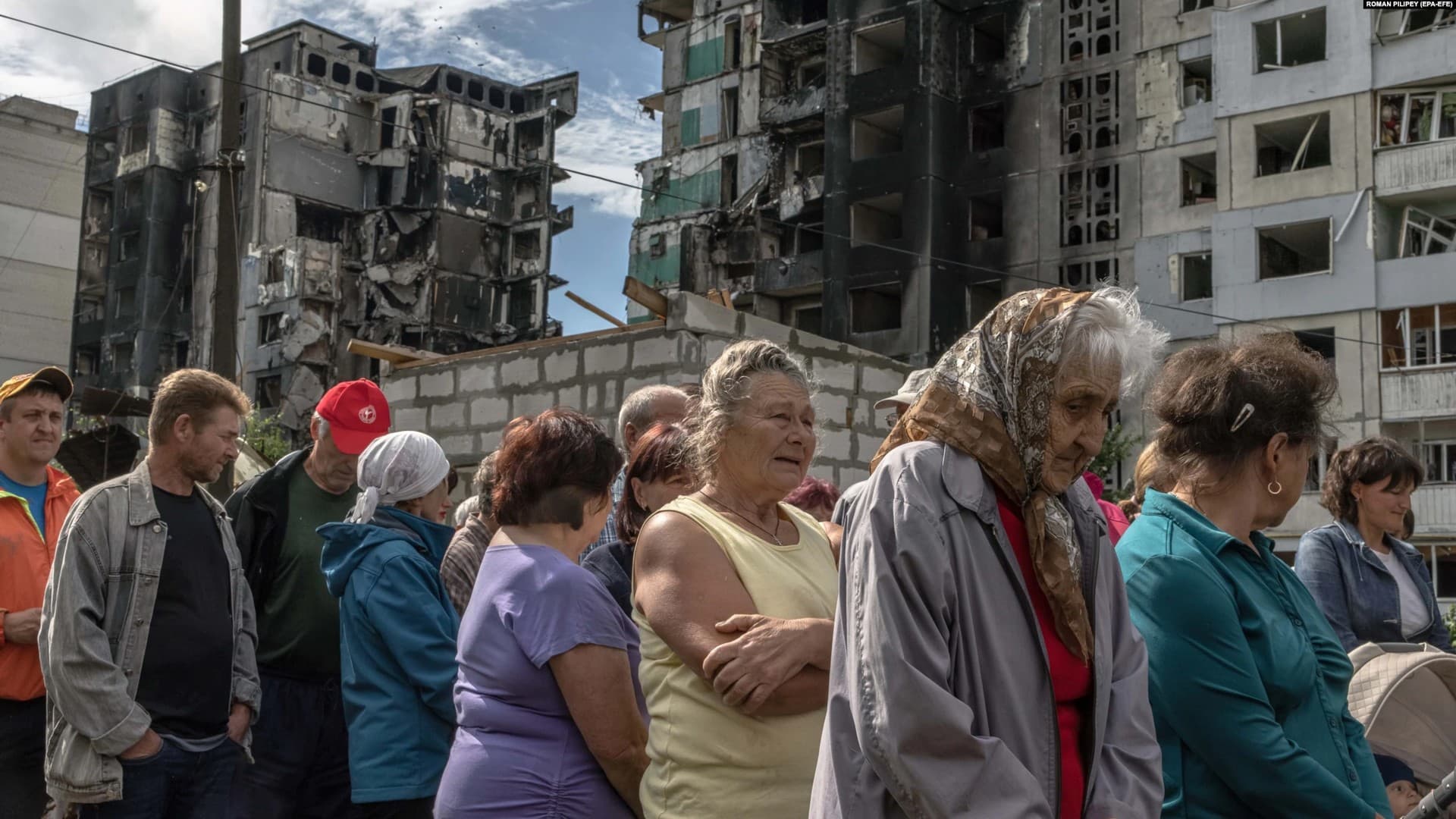 Residents wait to receive humanitarian aid in front of a building that was damaged during Russian shelling in Borodyanka