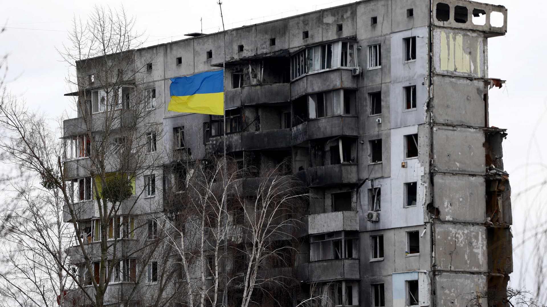 A Ukrainian national flag flies in front of a destroyed residential building in Borodianka