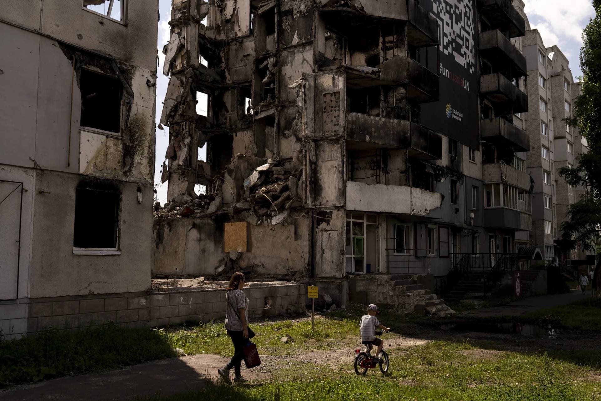 A woman and a boy make their way past an apartment building destroyed in Russian attacks in Borodyanka
