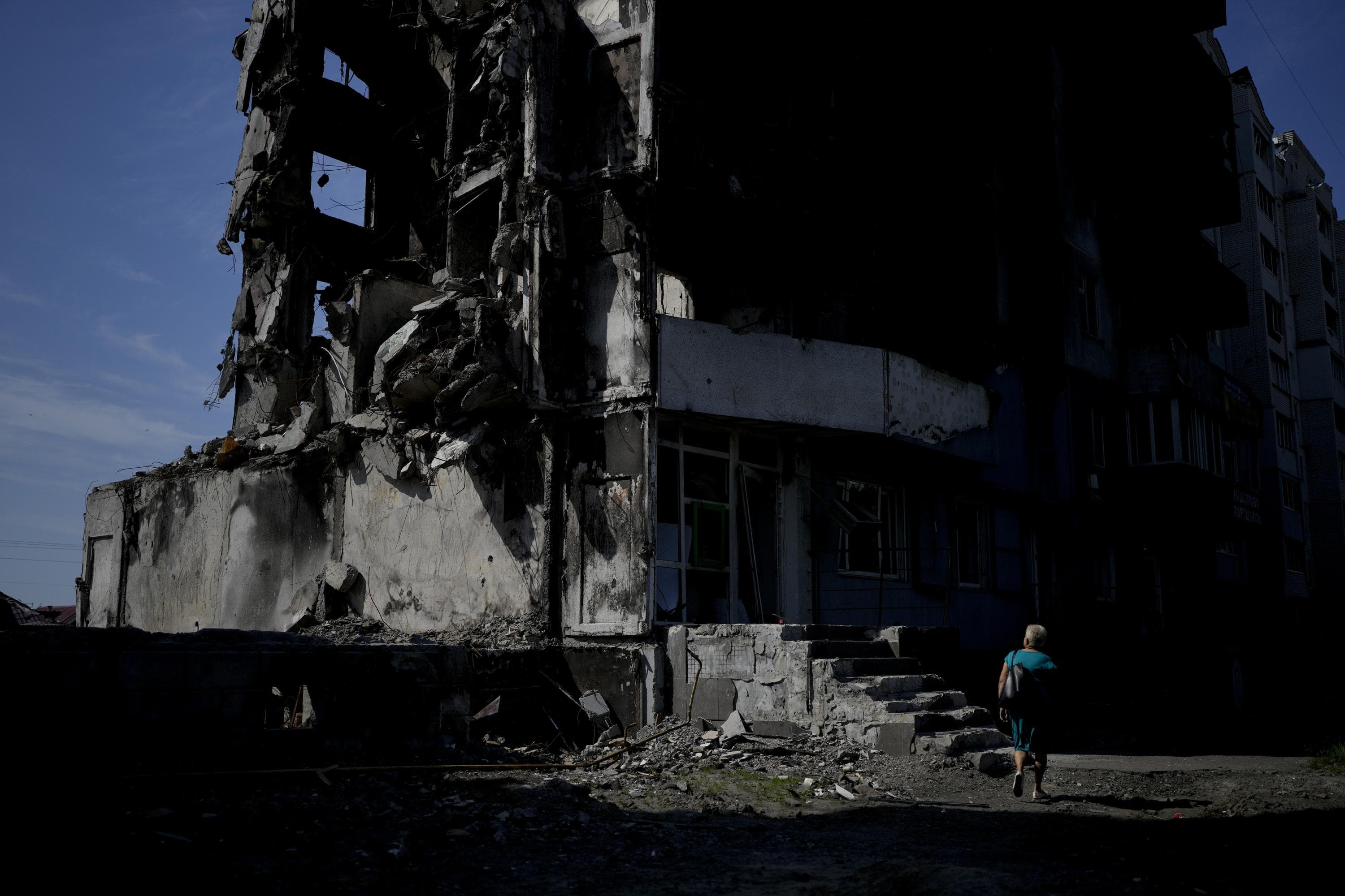 A woman walks past a building destroyed in Russian shelling in Borodyanka