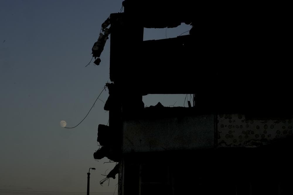 The moon is seen near a building destroyed by attacks in Borodyanka