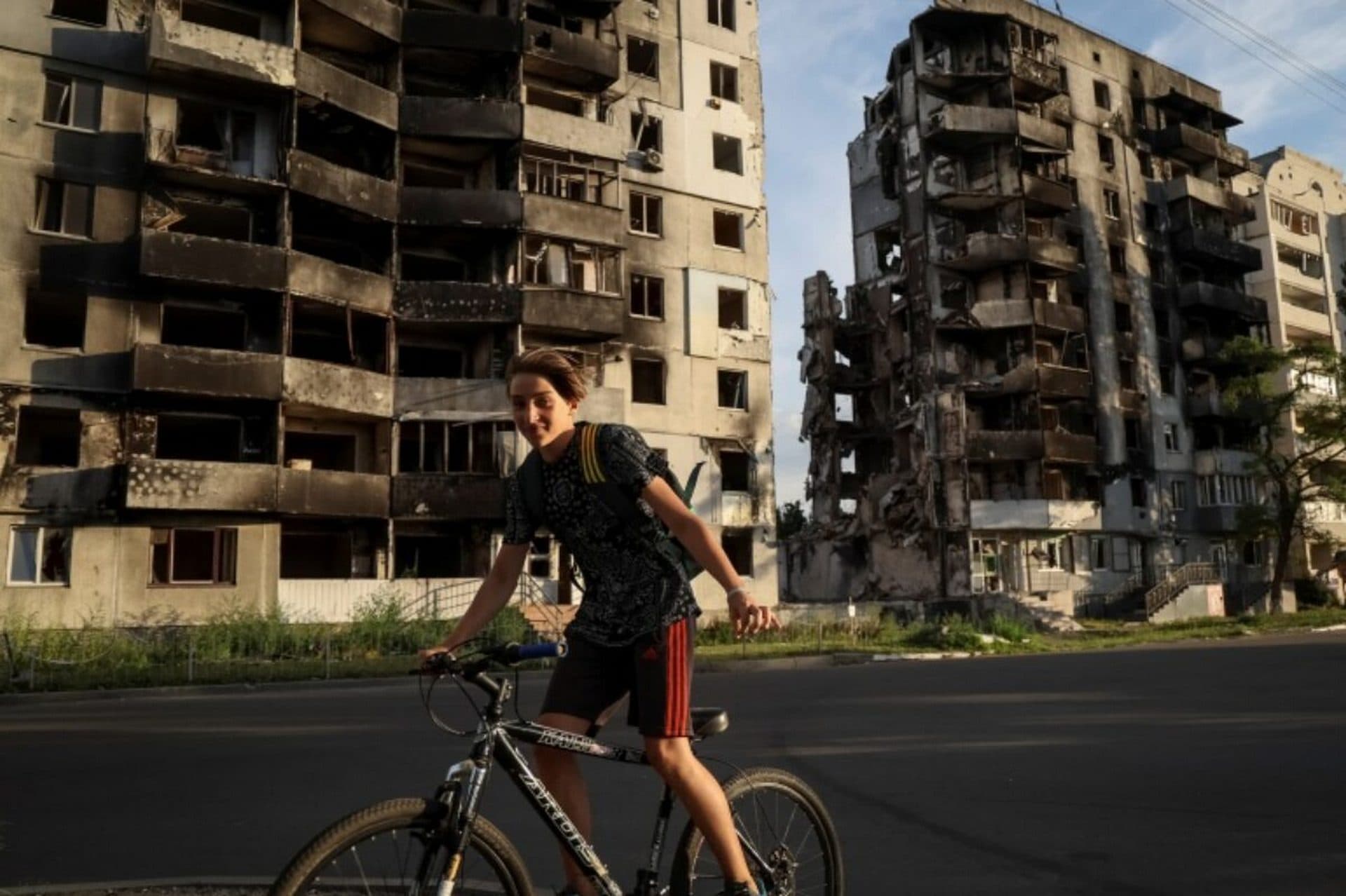 A boy cycles in front of destroyed buildings amid Russia's invasion of Ukraine, in the town of Borodyanka