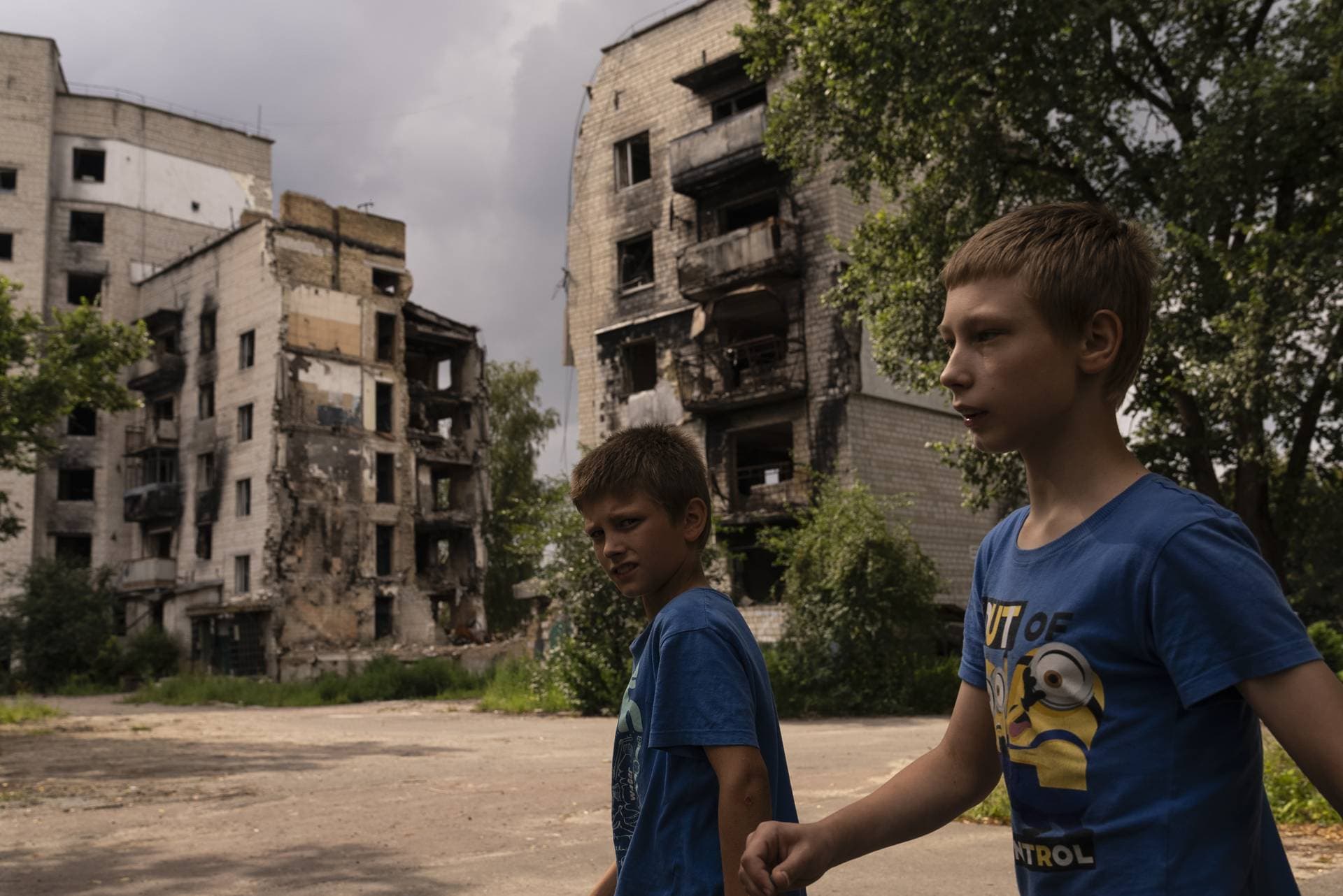 Two boys walk towards a playground past apartment buildings destroyed in Russian attacks in Borodyanka