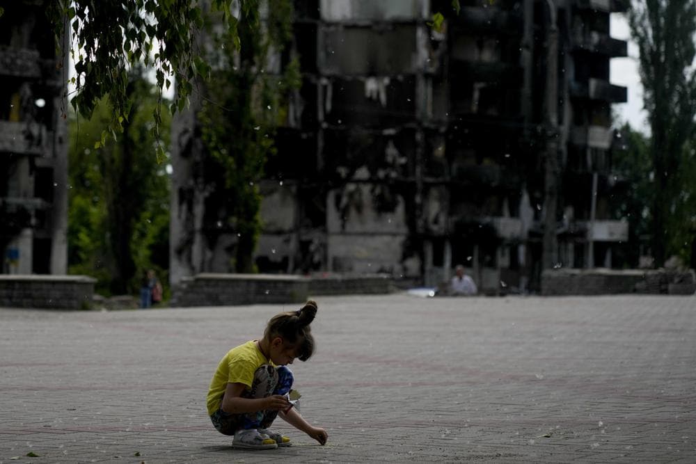 A girl plays at a square near buildings destroyed during attacks in Borodyanka