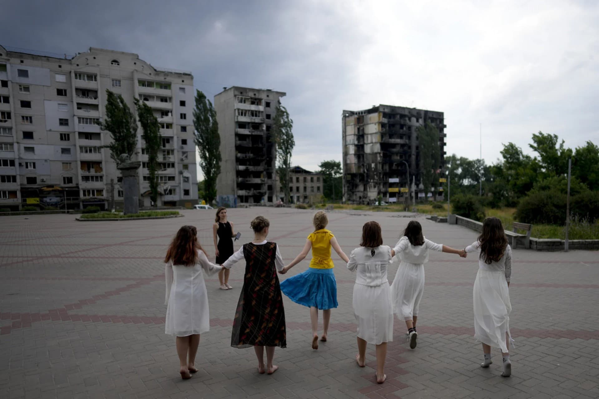 Girls dance near a building destroyed in Russian attacks, in Borodyanka