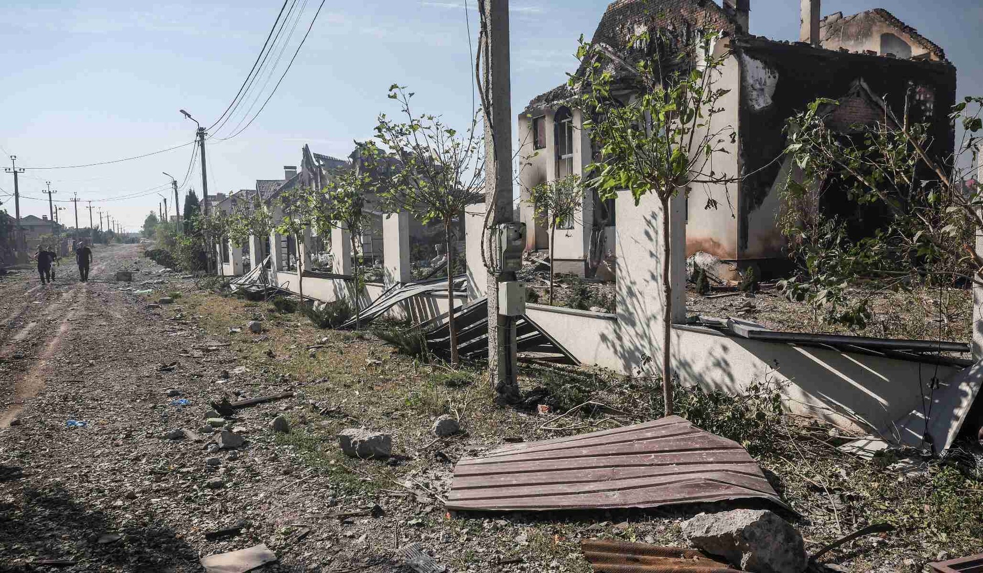 People walk past homes damaged in a Russian drone strike in Myla, Kyiv region