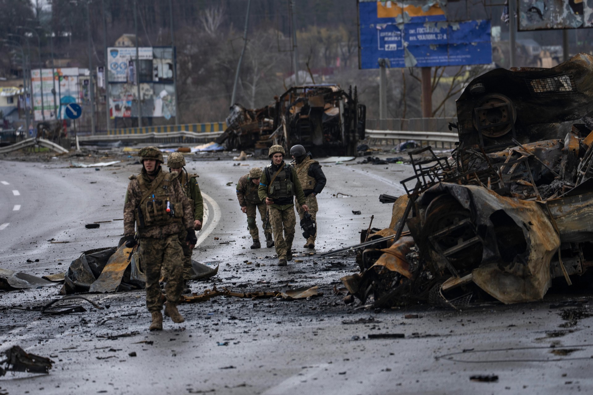 Ukrainian soldiers walk next to destroyed Russian armoured vehicles