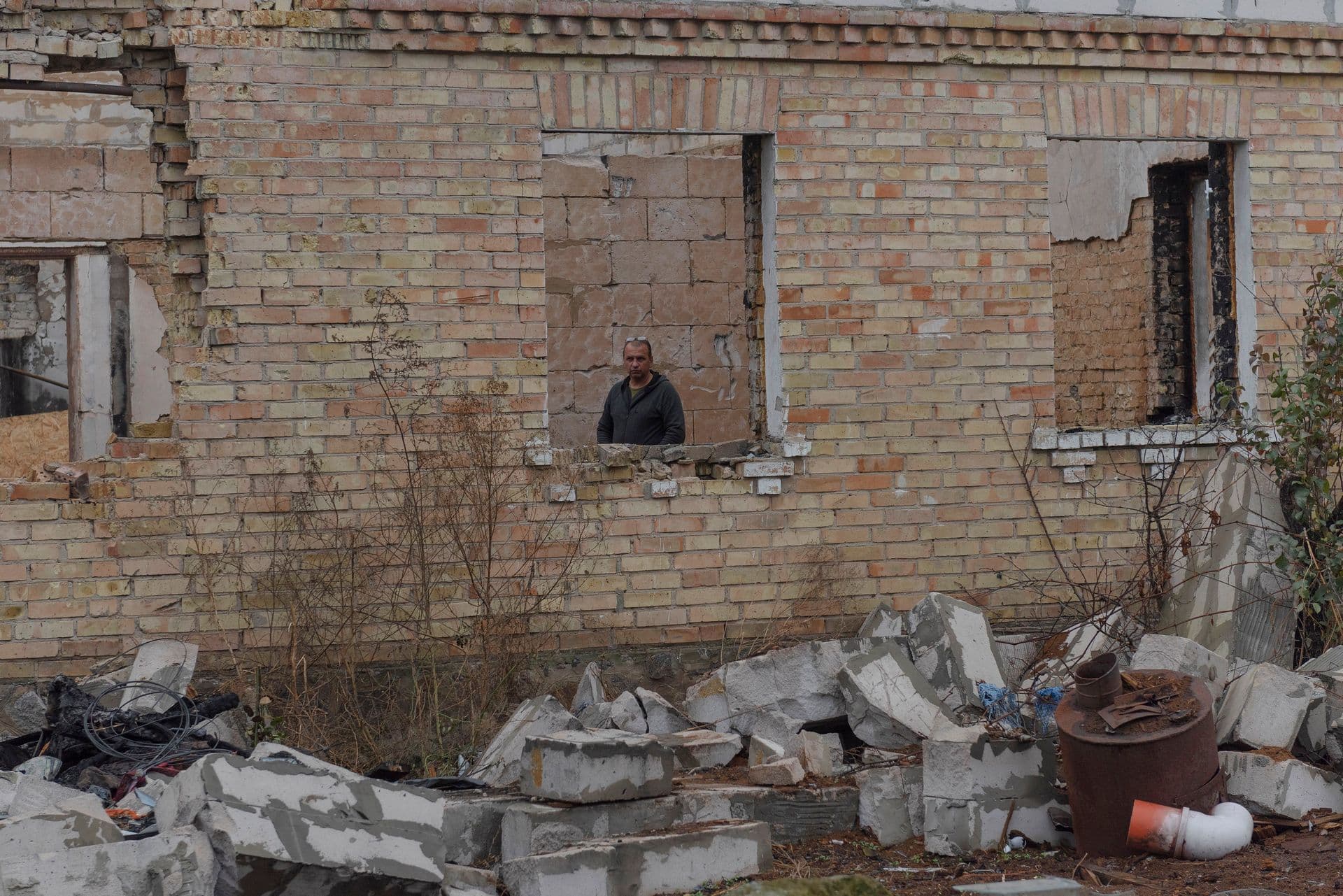 Vadym Zherdetsky is seen in a window of his house destroyed by fighting, in the village of Moshchun