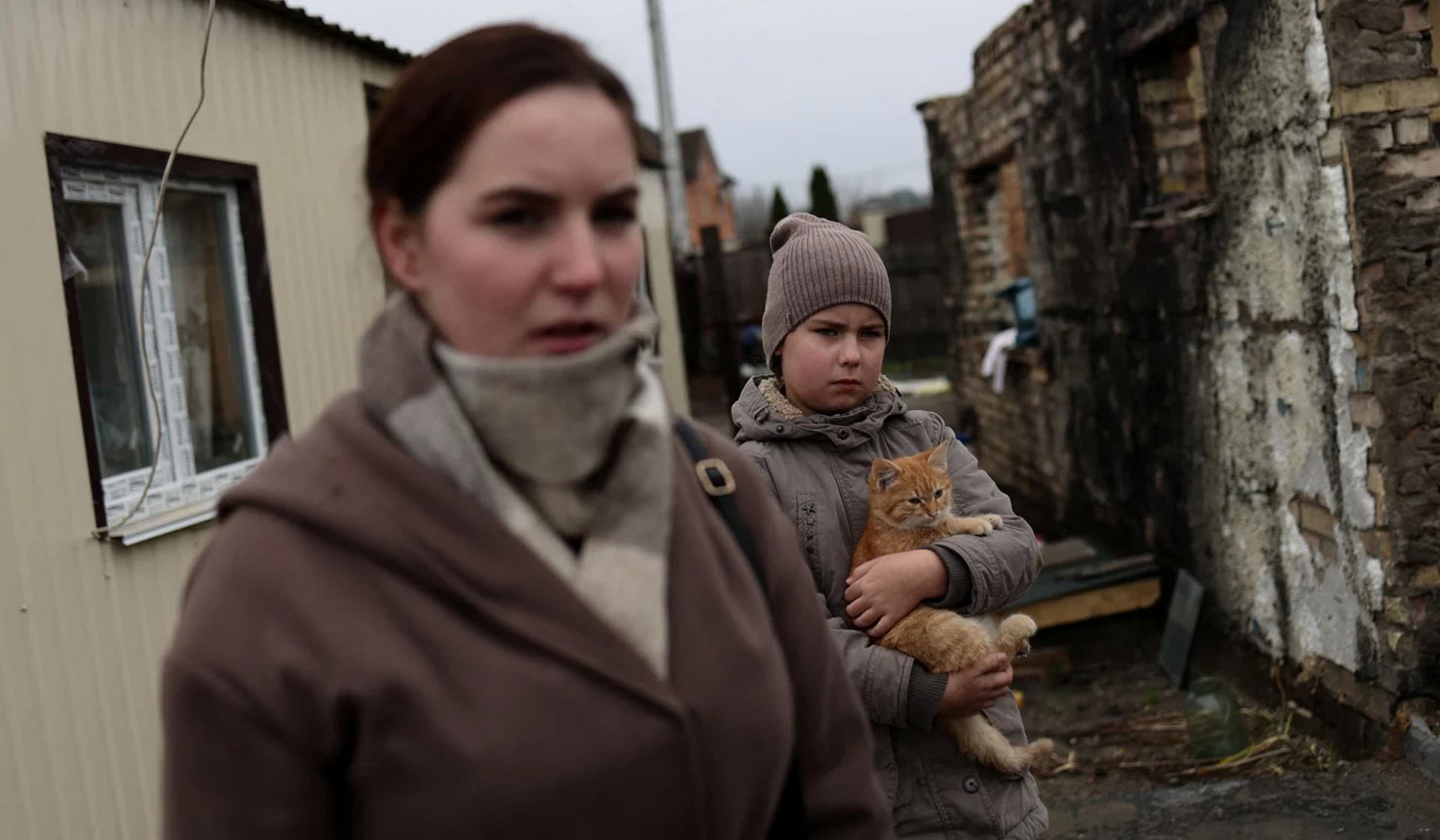 Kateryna Tyshchenko, accompanied by her 9-year-old half-sister Yuliia Zaika, stands outside her prefabricated accommodation which was built next to her destroyed house in the village of Moshchun