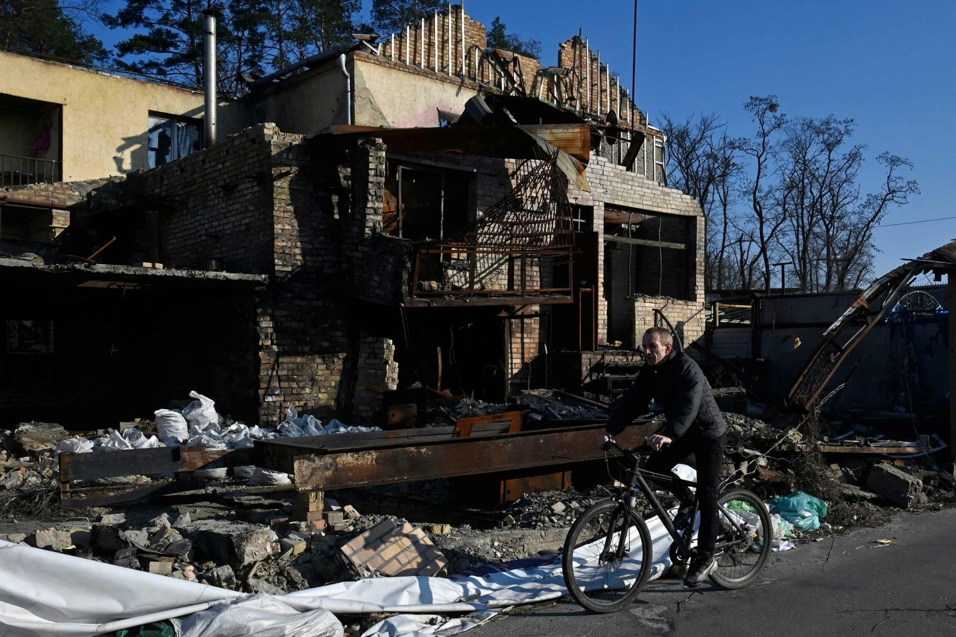 A cyclist rides on a bicycle past a house destroyed by shelling in Hostomel