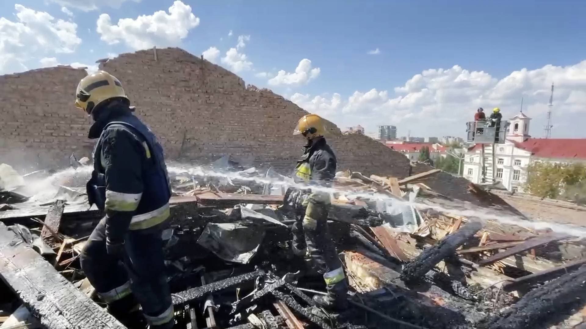 firefighters work on the roof of the Taras Shevchenko Chernihiv Regional Academic Music and Drama Theatre damaged by Russian attack in Chernihiv