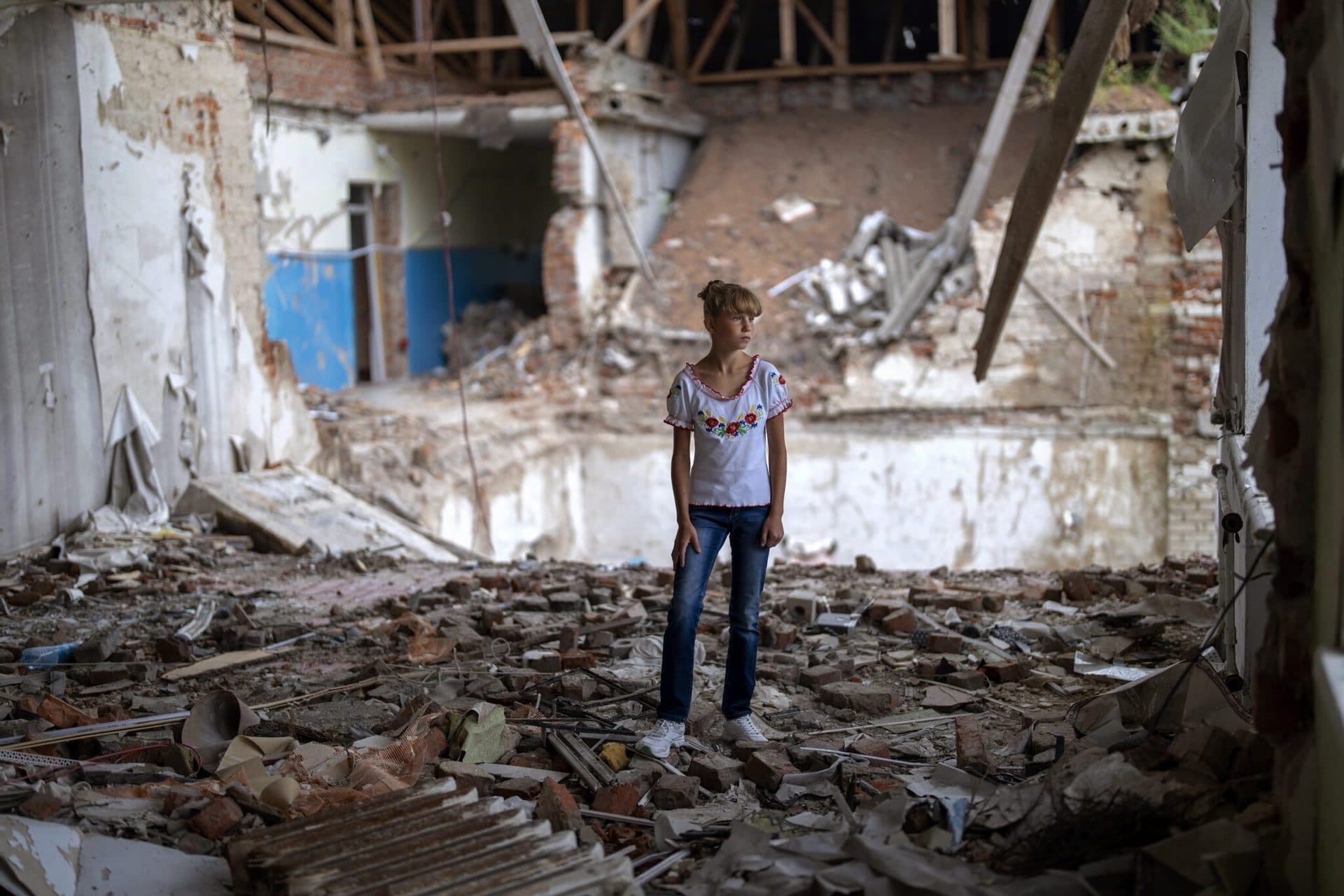 Sofia Klyshnia stands in the rubble of her former classroom, in the same position where her desk sat before the Mykhailo-Kotsyubynske's lyceum was bombed by Russian forces on March 4, in Chernihiv