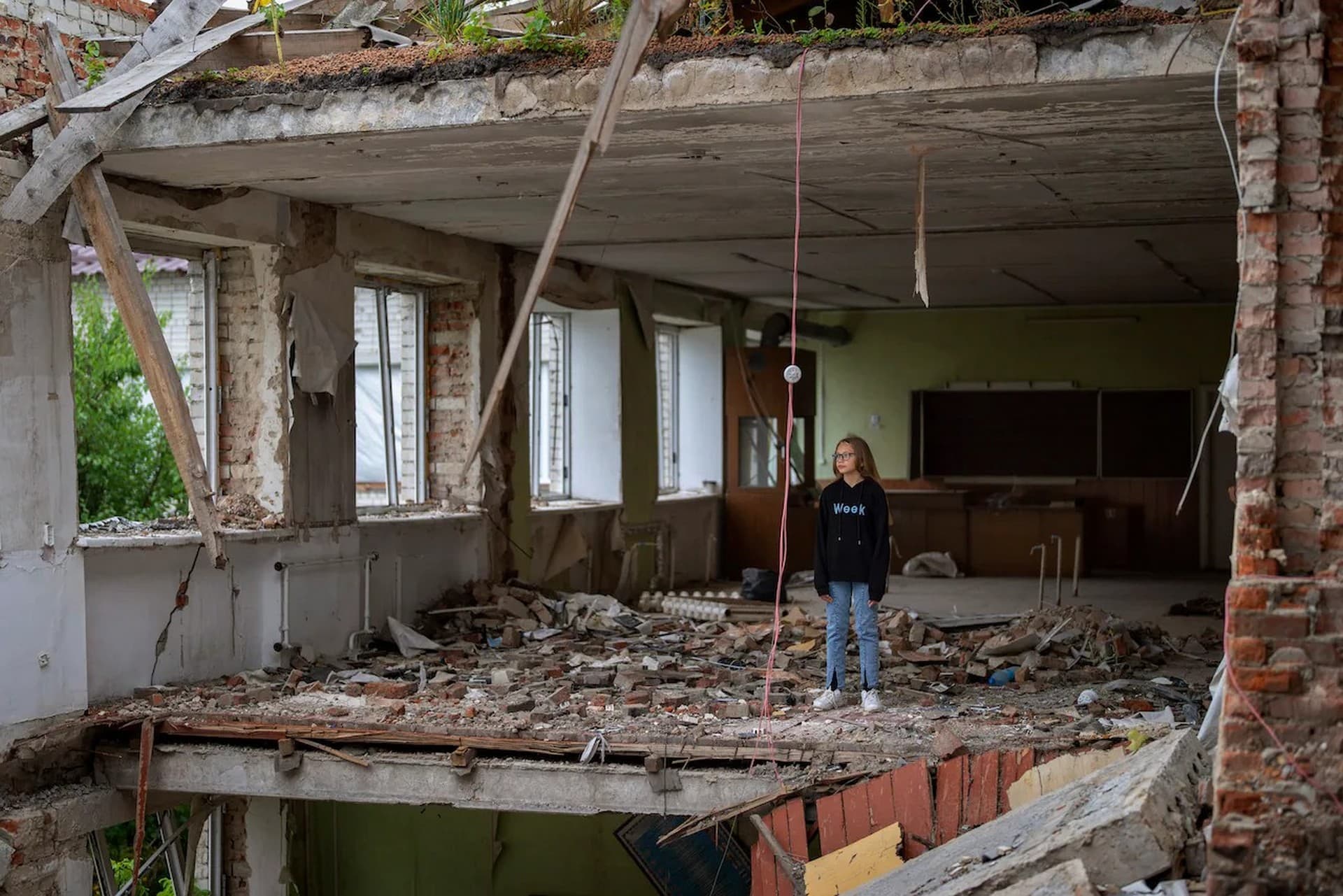 Anna Skiban stands in the rubble of her former classroom, in the same position where her desk sat before the Mykhailo-Kotsyubynske's lyceum was bombed by Russian forces on March 4, in Chernihiv