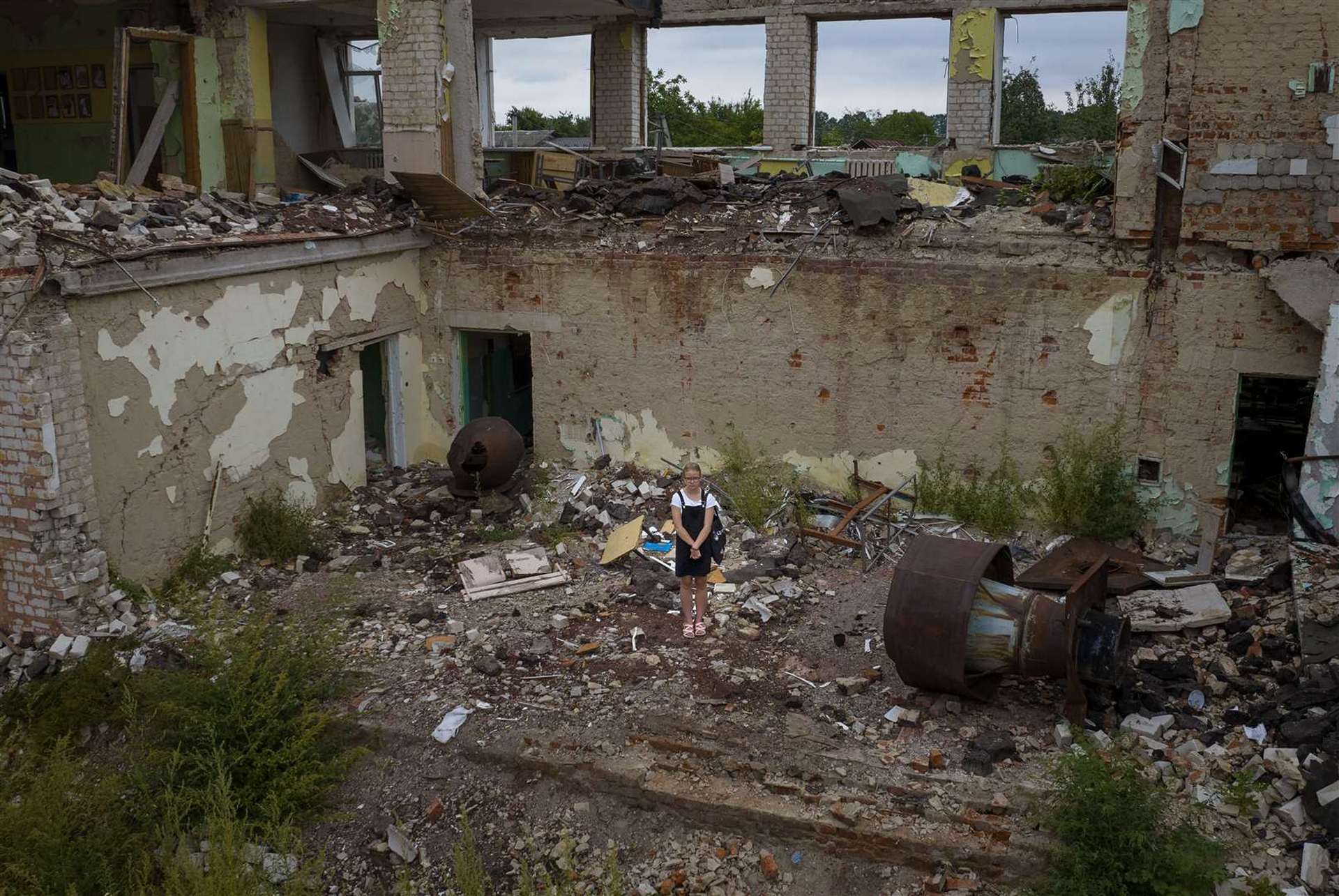 Anastasia Avramenko stands in the rubble of her former classroom, in the same position where her desk sat before the Chernihiv School #21