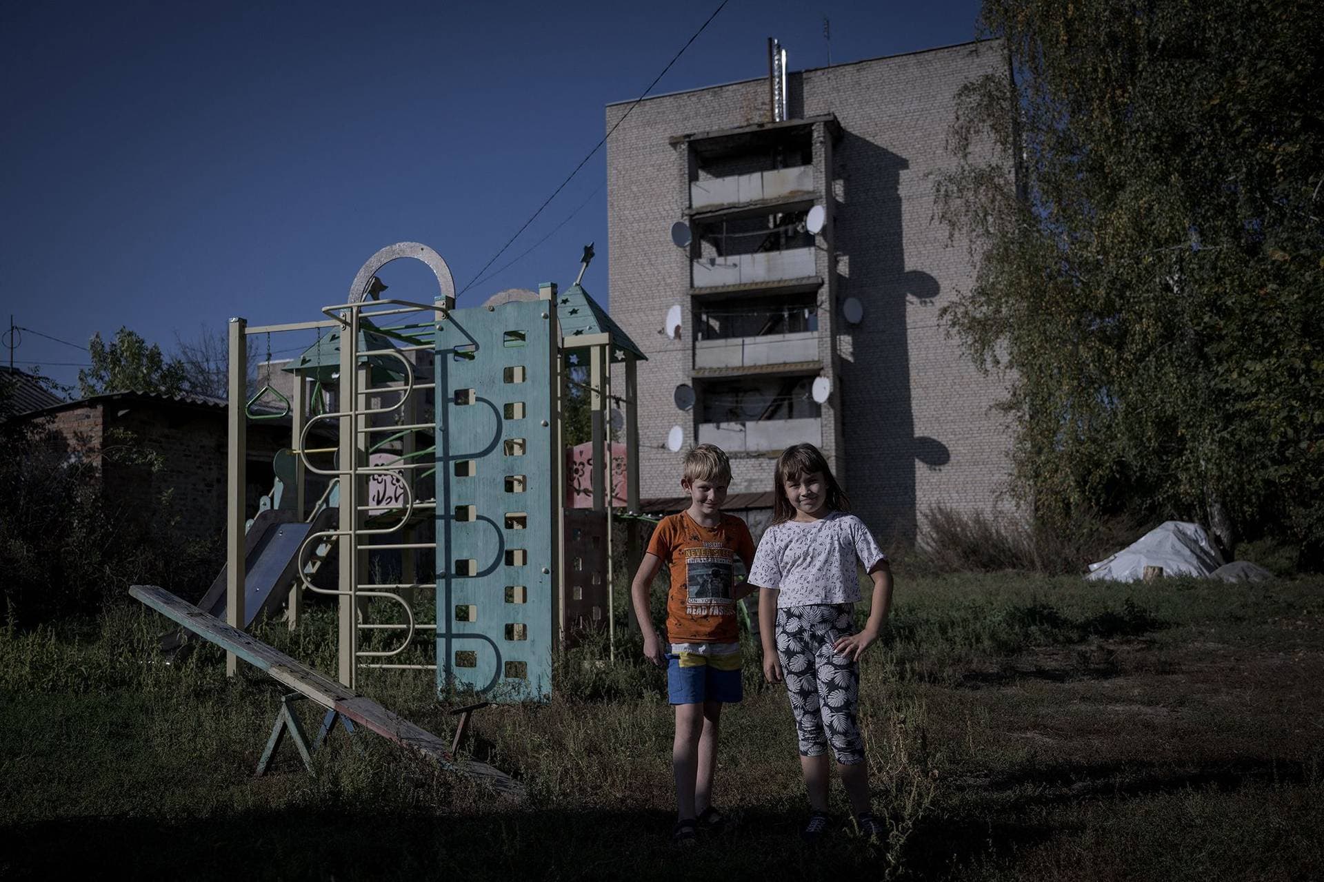 Children in front of a damaged residential building in the Staryi Saltiv town