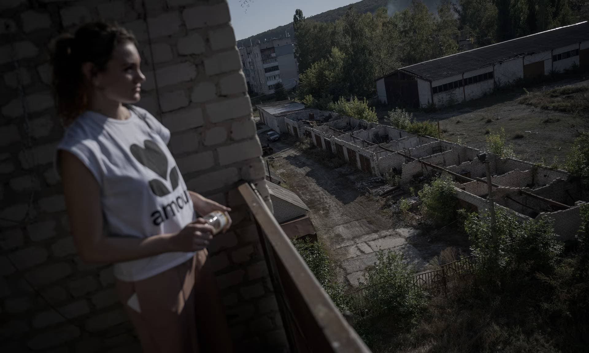 Alyona looks out from the balcony of her house damaged during the Russian attack in the Staryi Saltiv
