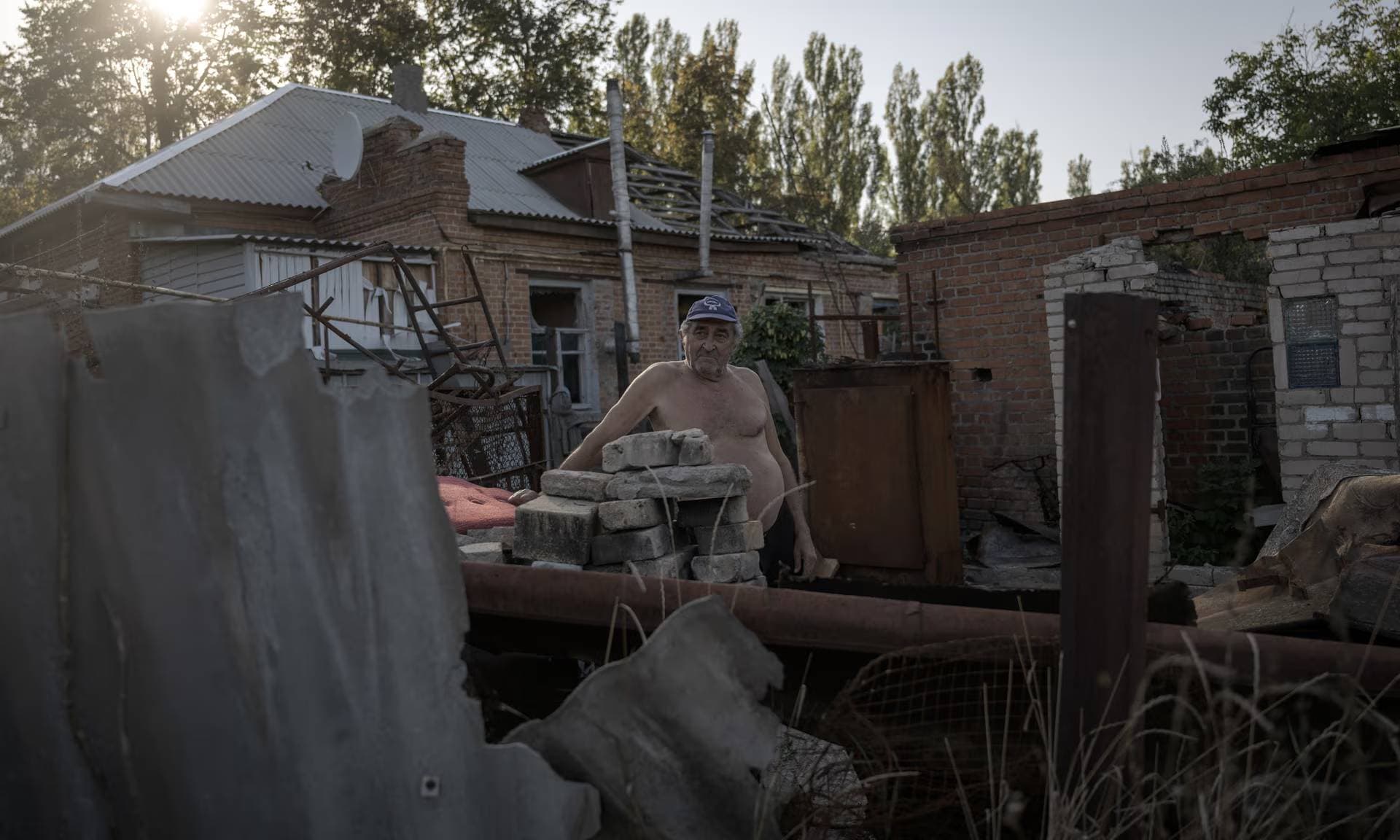 A man is seen in front of a damaged building in the Staryi Saltiv