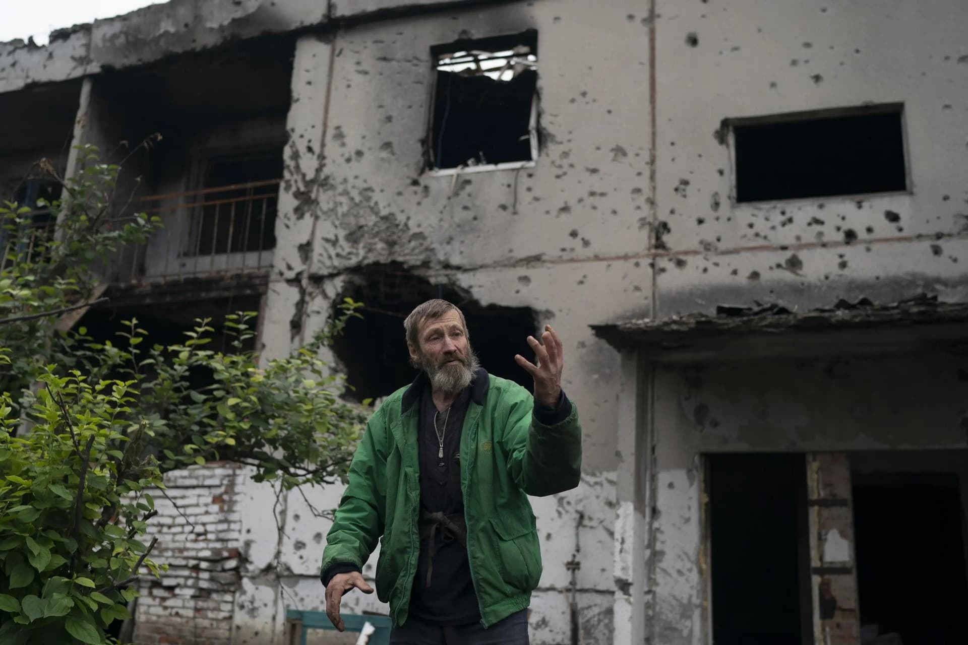 Viacheslav Myronenko stands in front of the entrance of a damaged building where he lives in the freed village of Hrakove