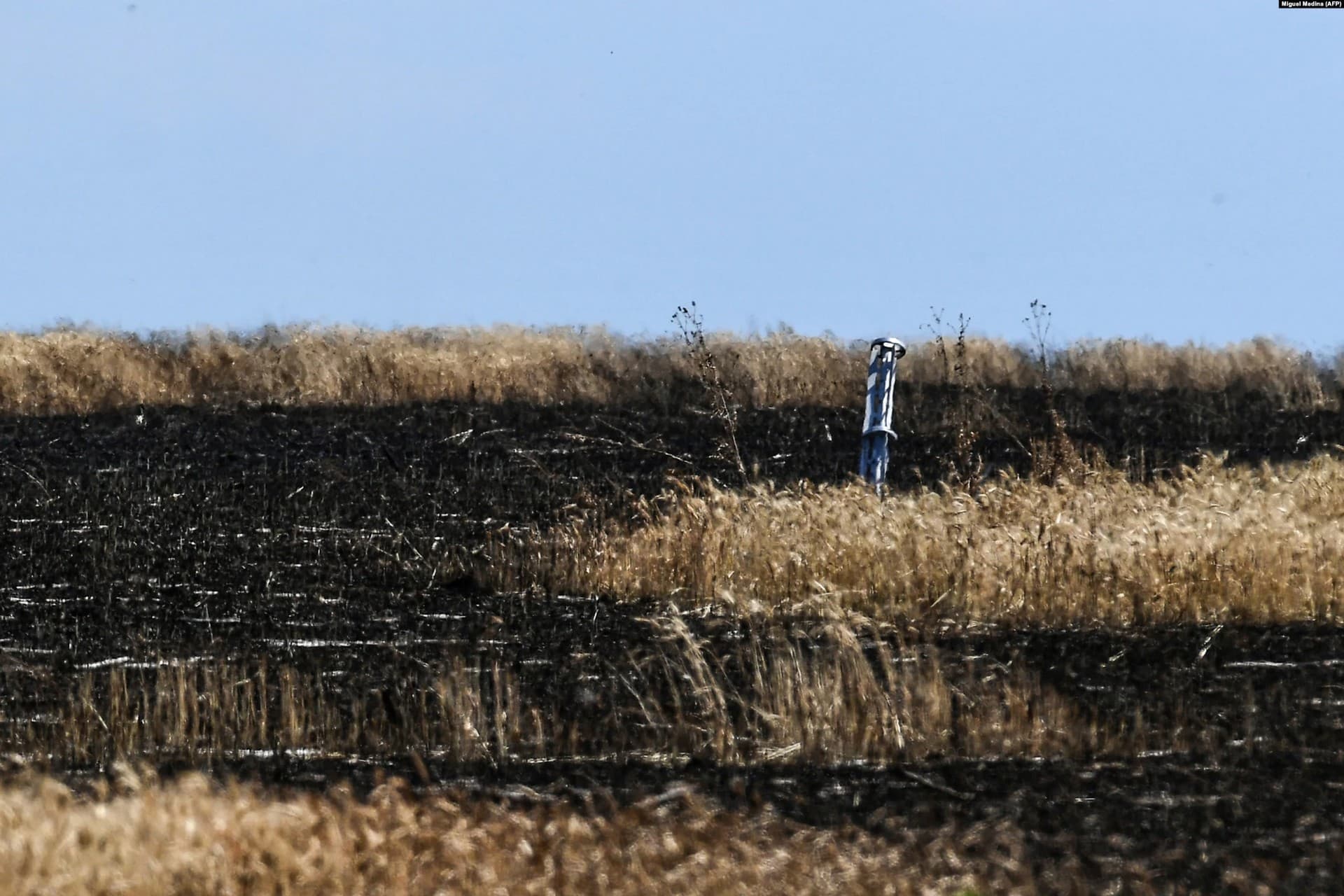 The internal section of a rocket embedded in a singed wheat field at an undisclosed location in Ukraine