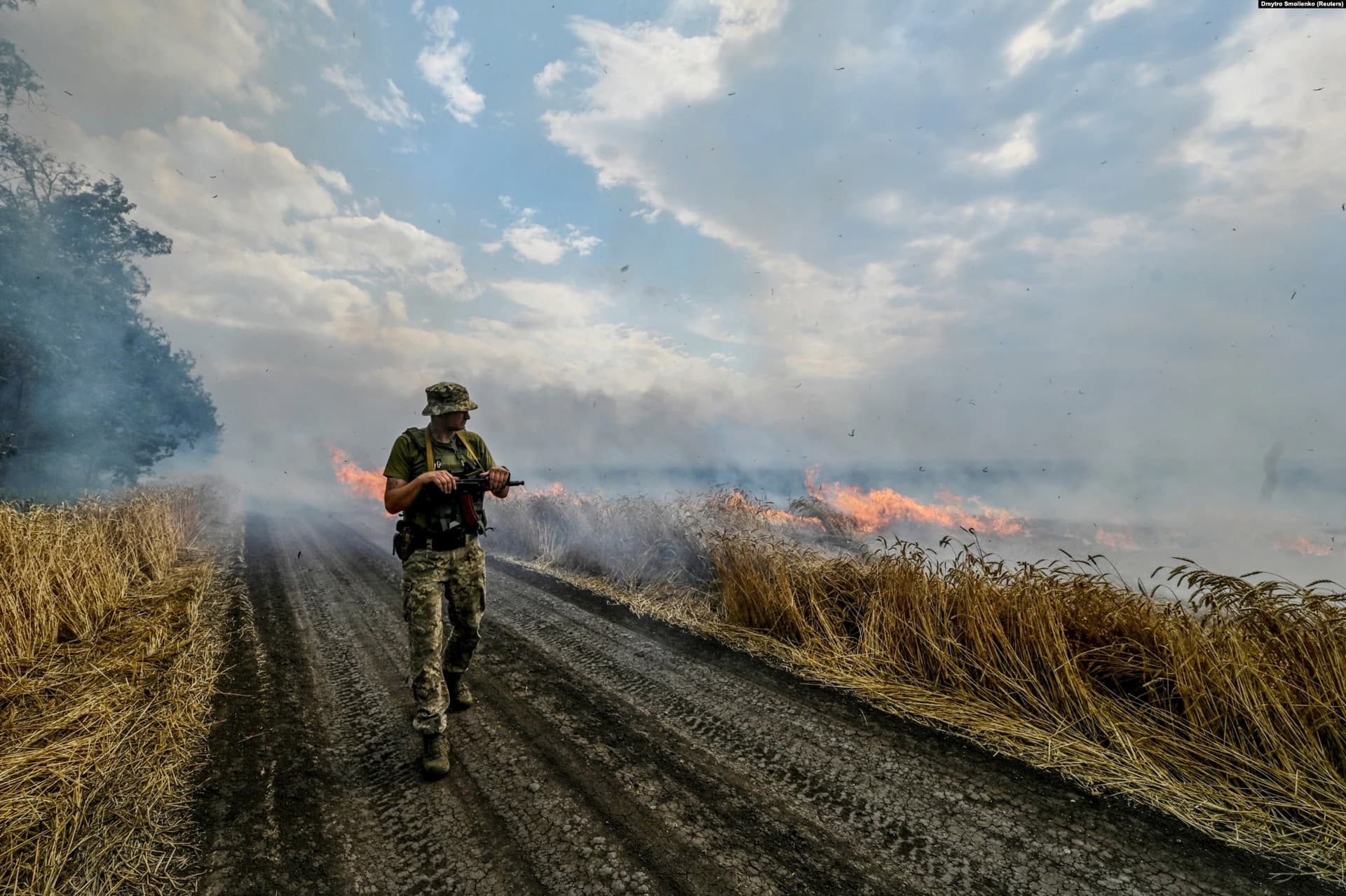 A Ukrainian fighter walks past a burning wheat field in eastern Ukraine near the front lines of the Russian advance on July 17