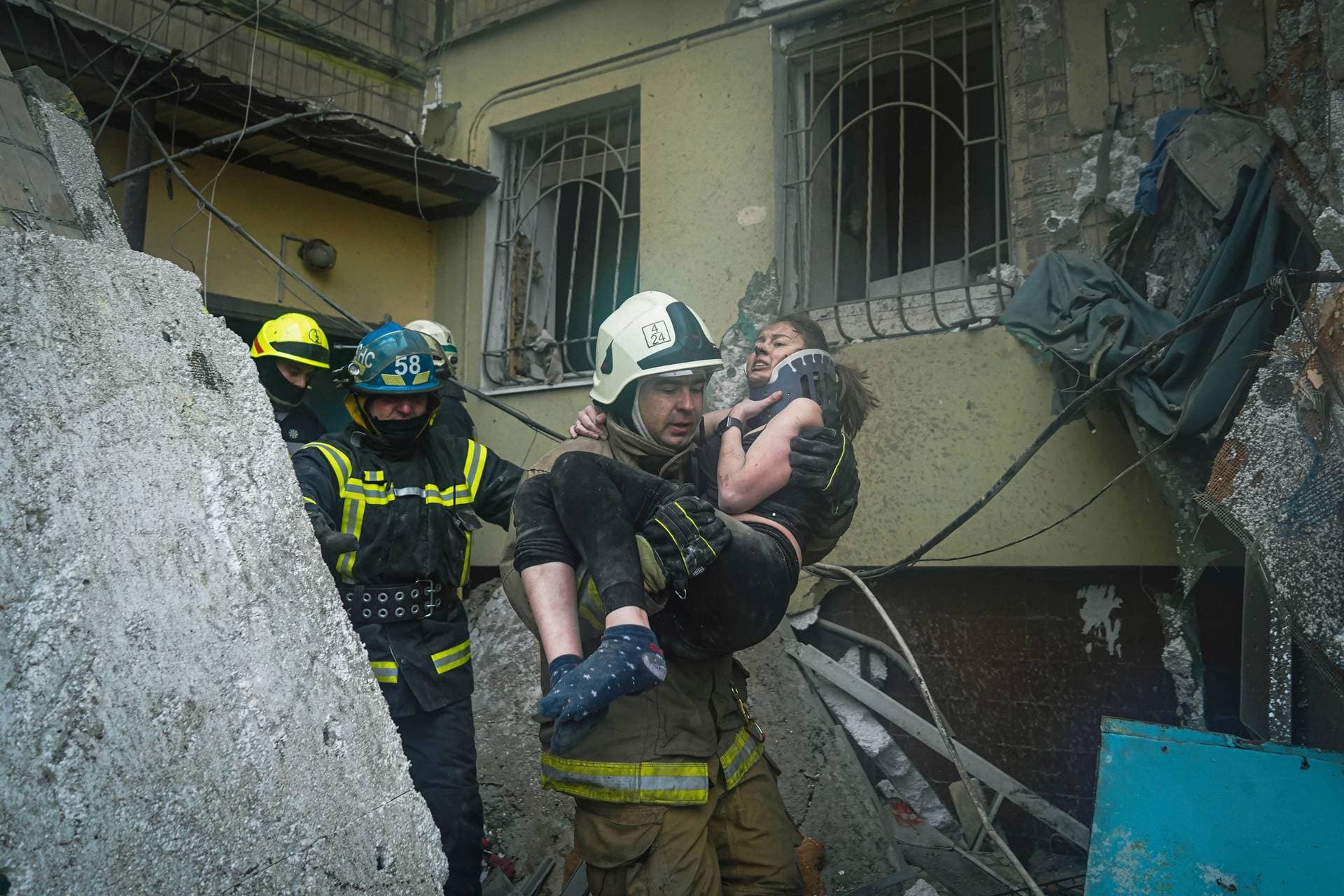 Ukrainian firefighter carries a wounded woman out of the rubble from a building in Dnipro